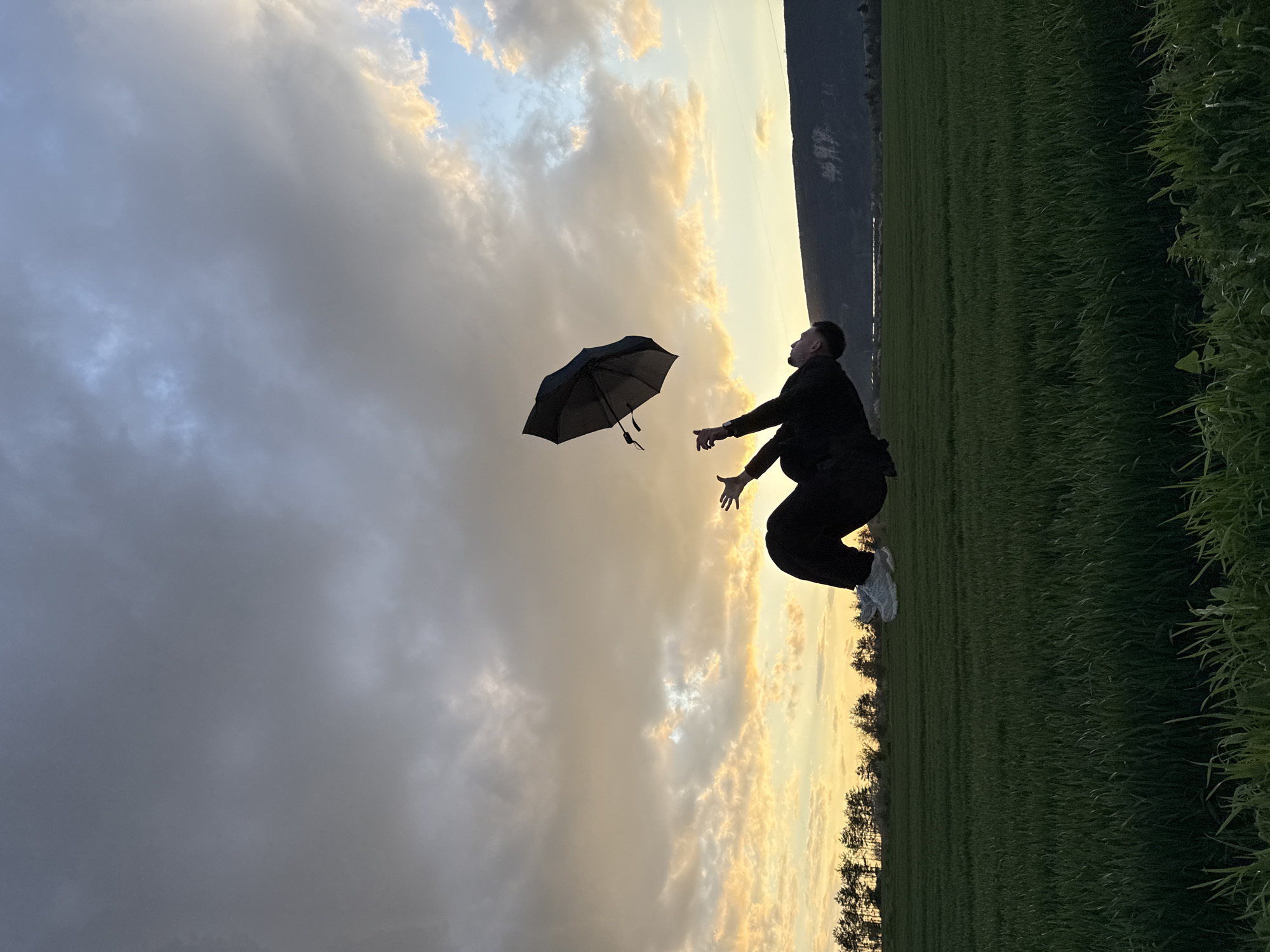 Person chases falling umbrella in Bulgarian field at sunset