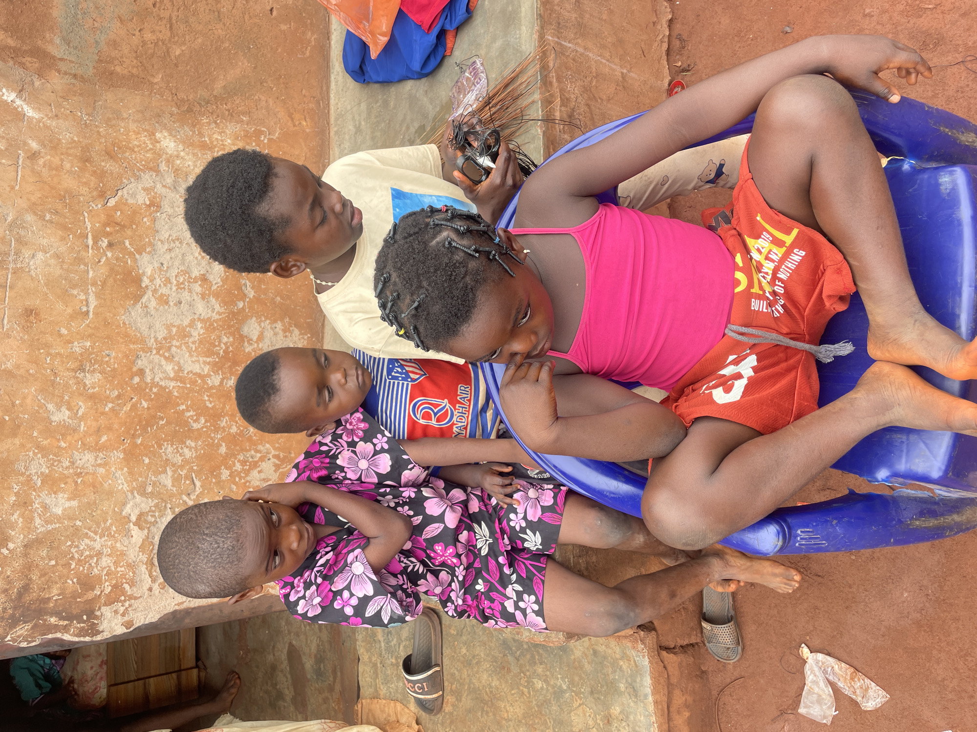Children gather outdoors, drink water in Ogbe Nigeria morning