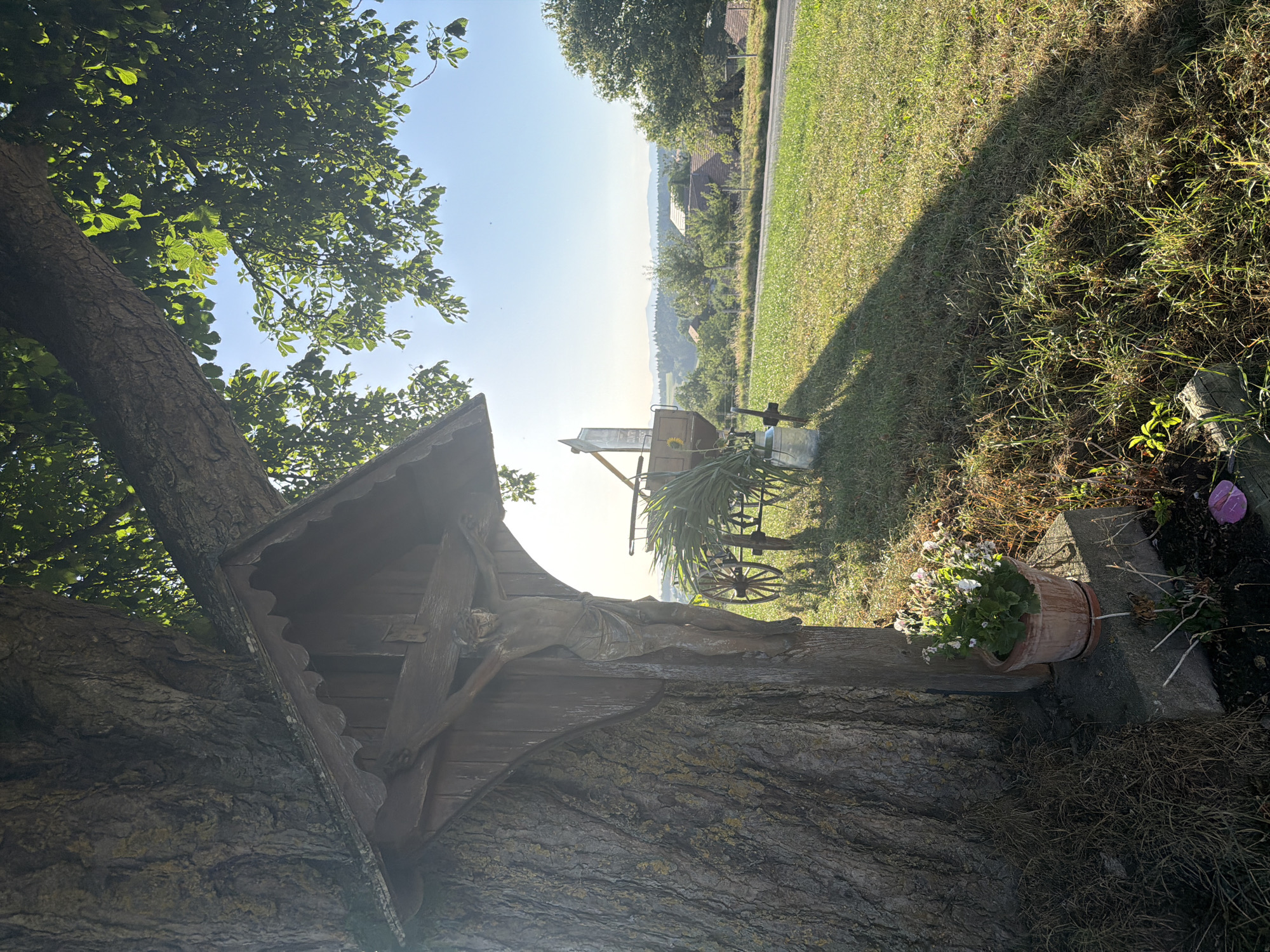 Vintage carriage, wayside shrine, and summer afternoon in Ufhusen