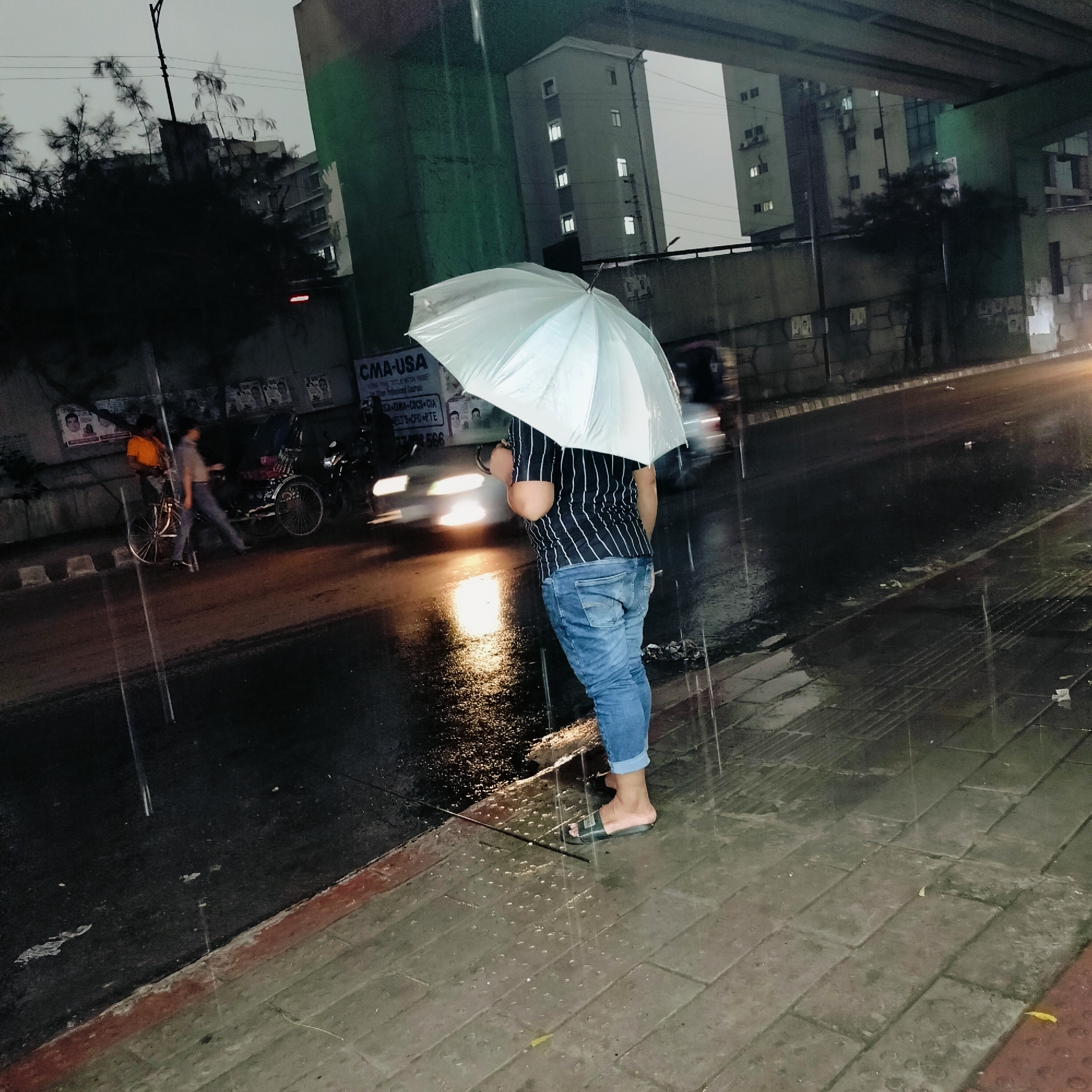 Person tends to storm drain during heavy rain in Dhaka