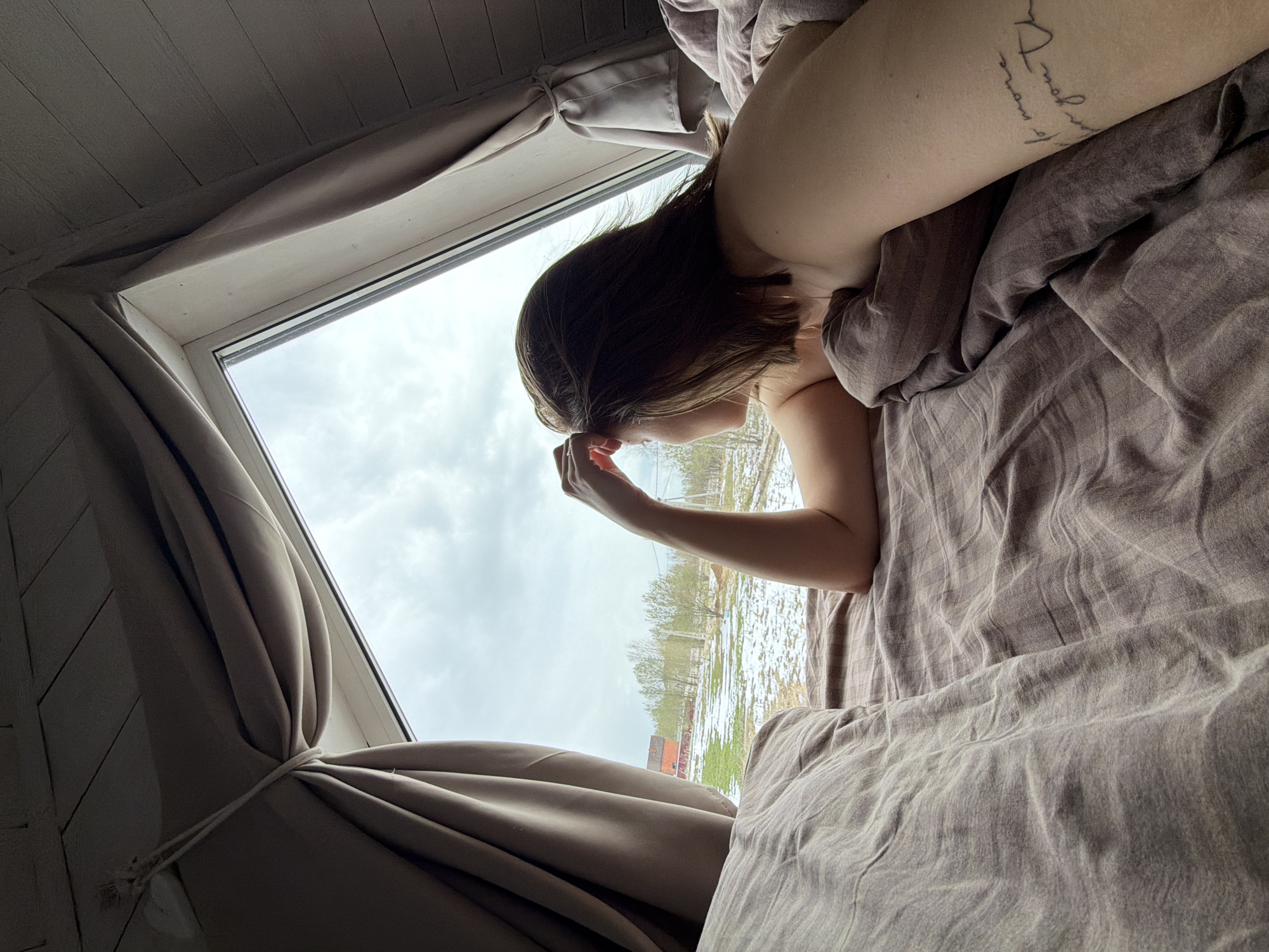 Person rests in bed on overcast morning in Бунятино