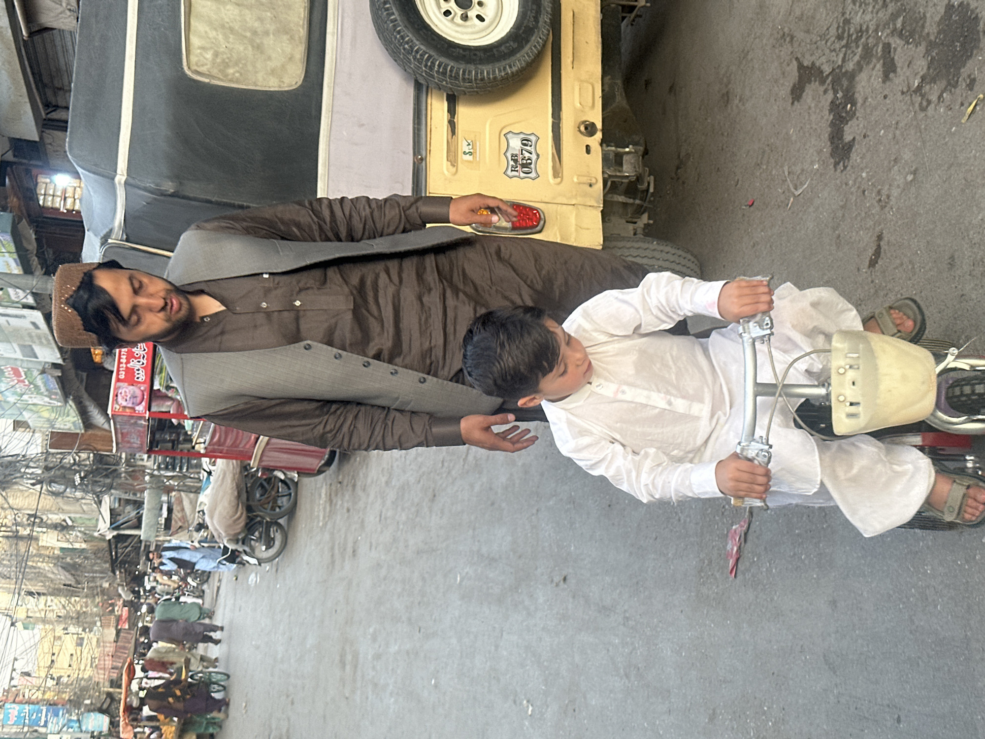 Child operates red vehicle near street vendor in Quetta
