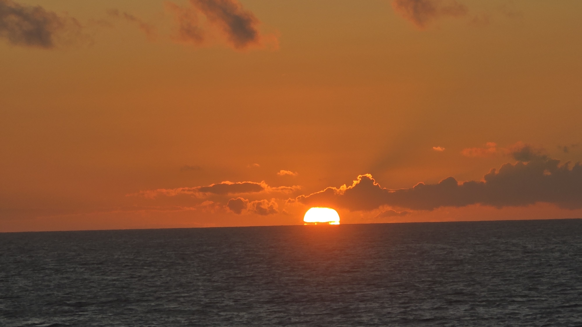 Orange sunset drops below the ocean horizon off Scotland