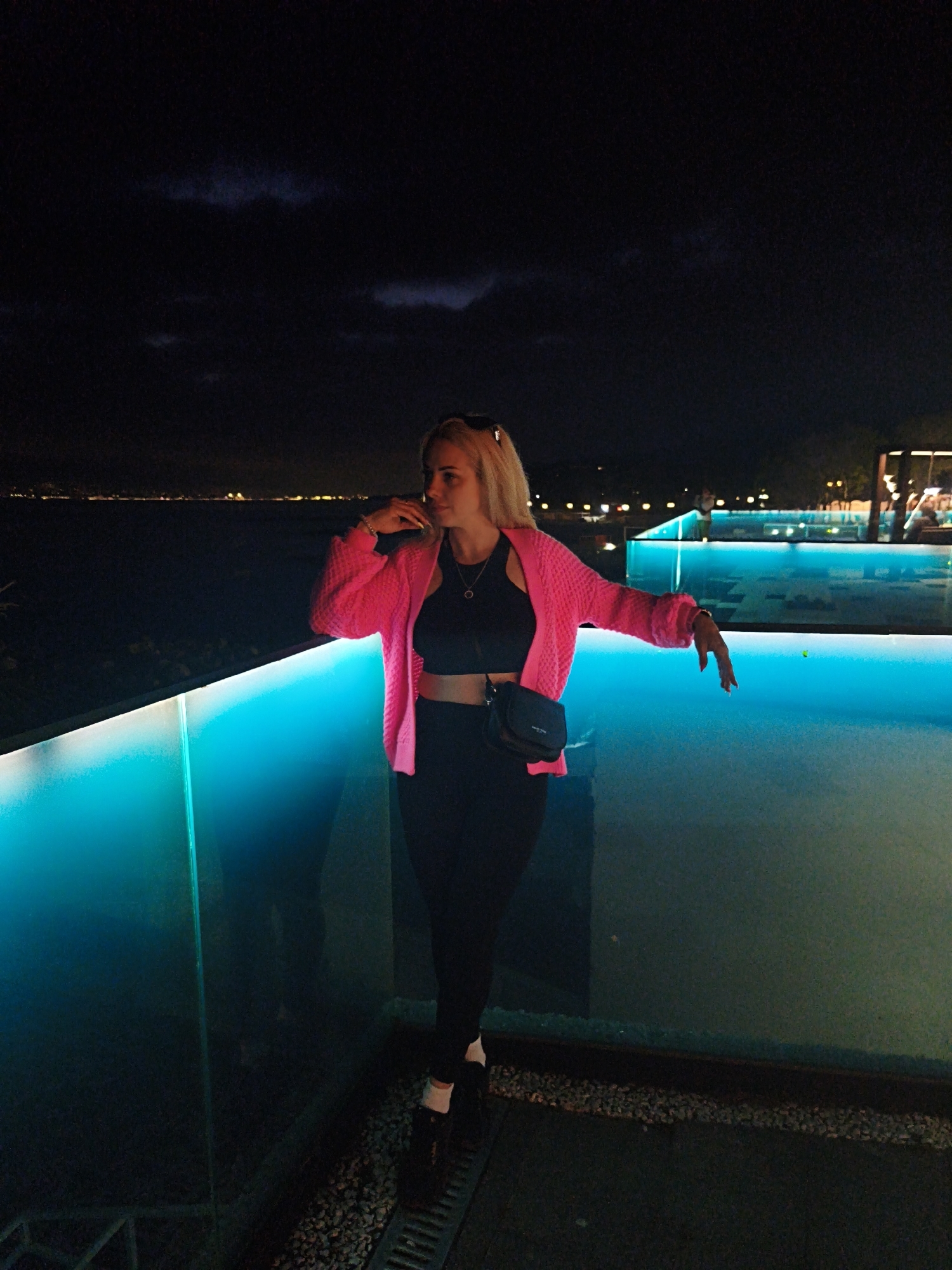Woman observed on balcony overlooking illuminated pool in Novorossiysk