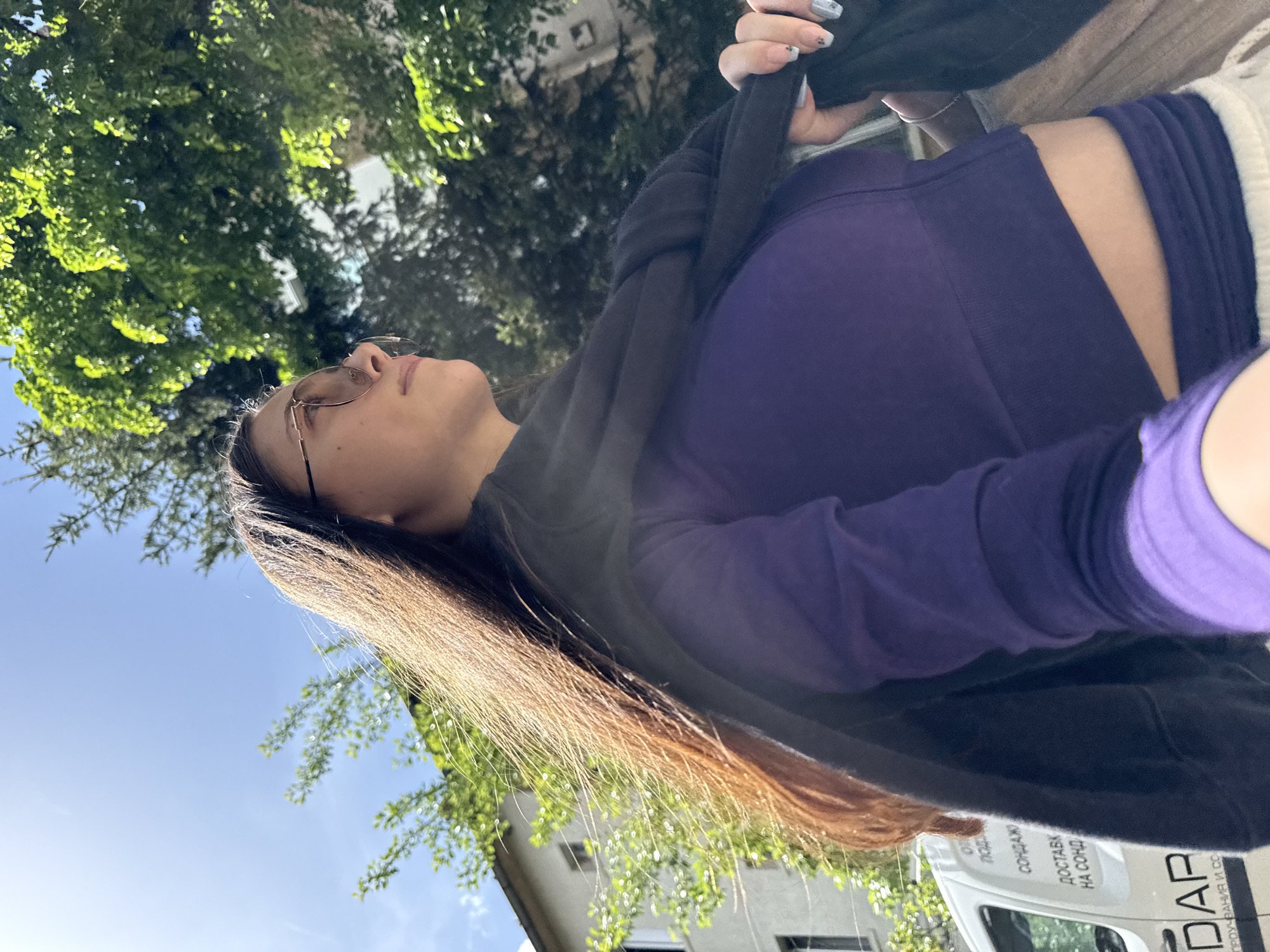 Woman looks skyward while standing under trees in Sofia