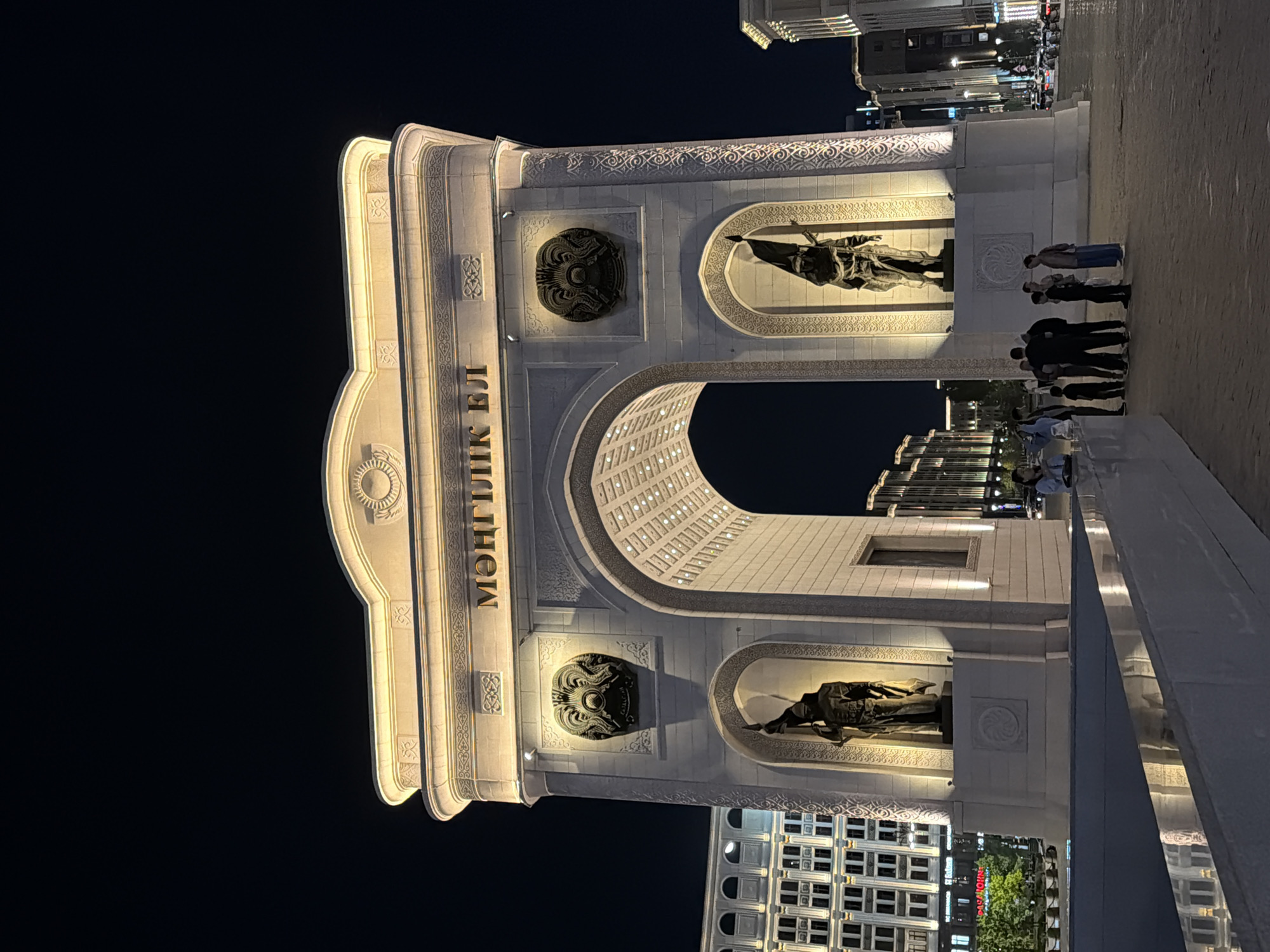 Mongolian National Arch glowing under golden night lights in Astana