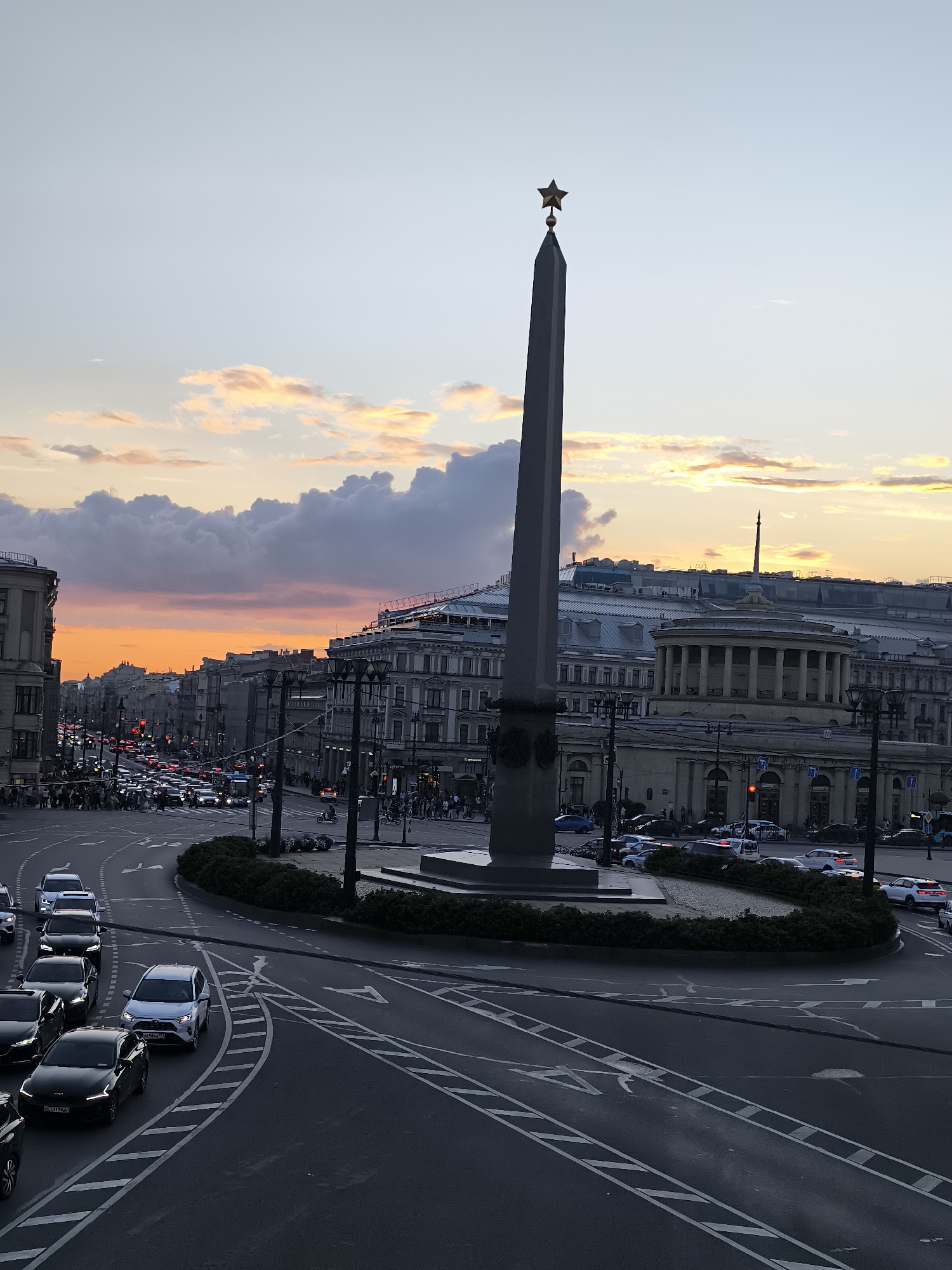 Star-topped obelisk at a Saint Petersburg intersection, golden hour