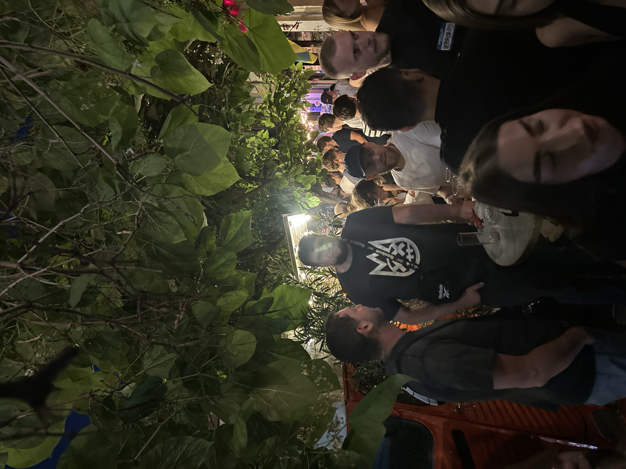 Lively nighttime bar patio gathering with crowds and ambient lighting