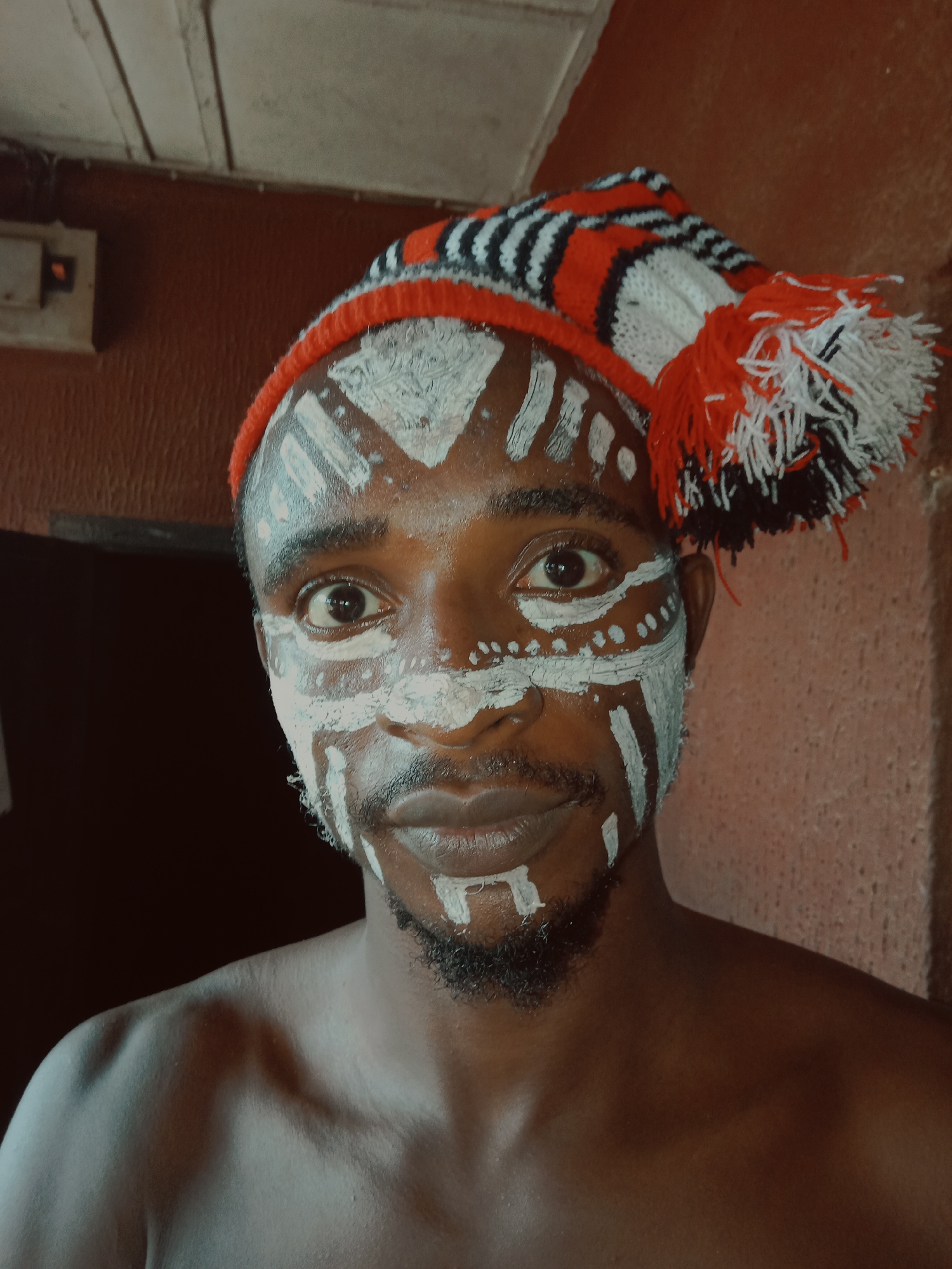 Person in tribal face paint and striped hat documented