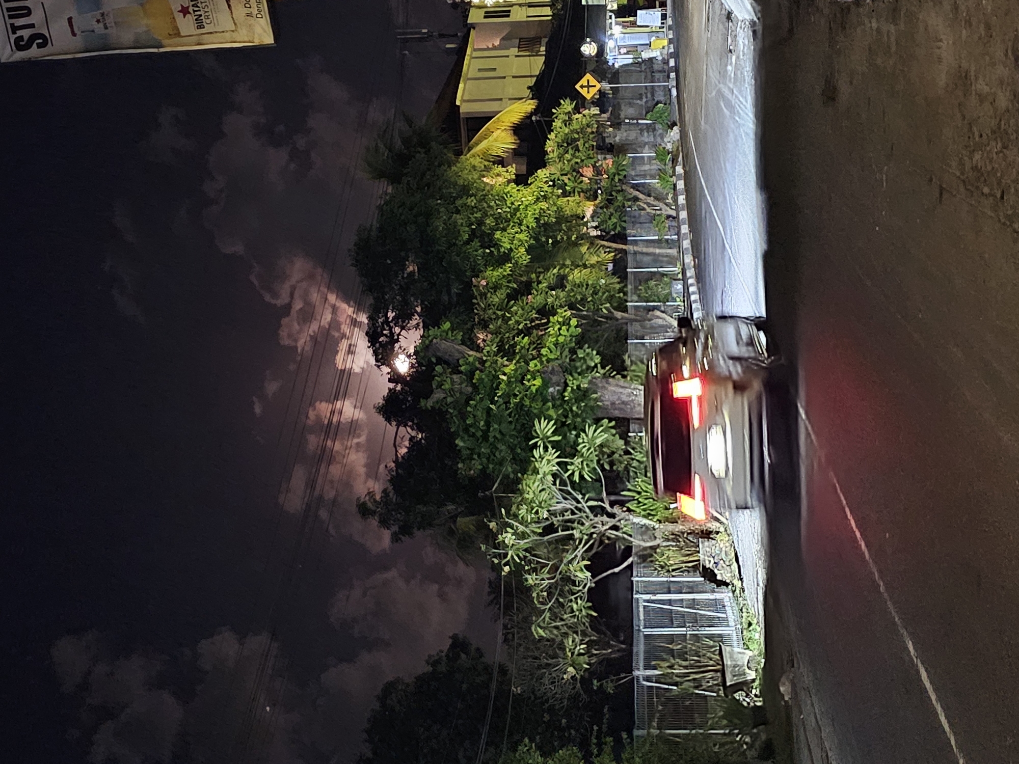 Full moon rising over Denpasar streets, framed by wires and trees