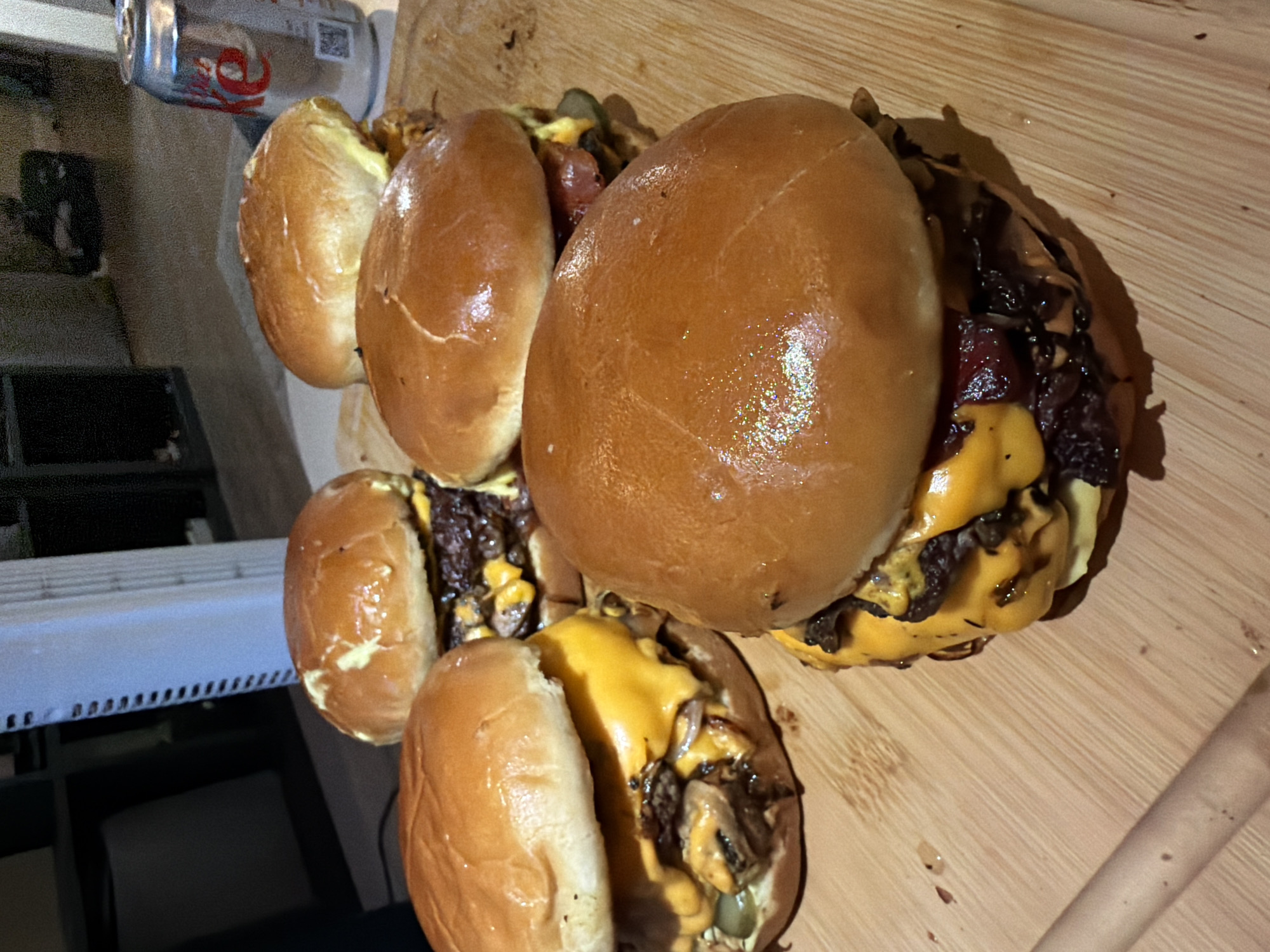 Five cheeseburgers and a Coke laid out on a cutting board