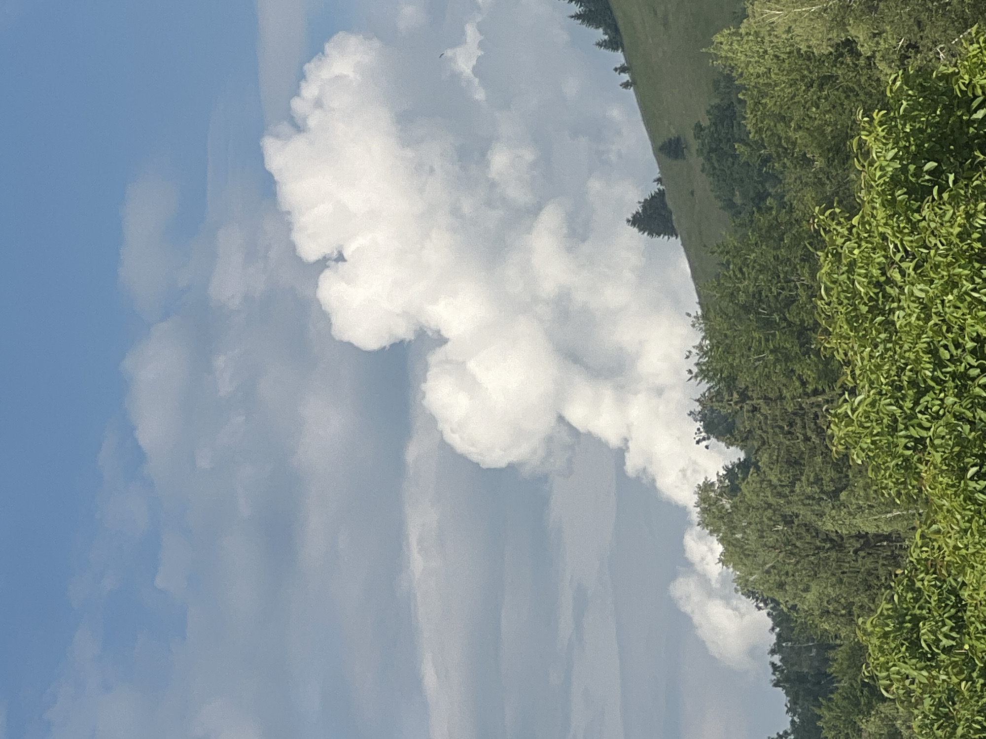 Green hills, village rooftops, and shifting skies on a summer afternoon