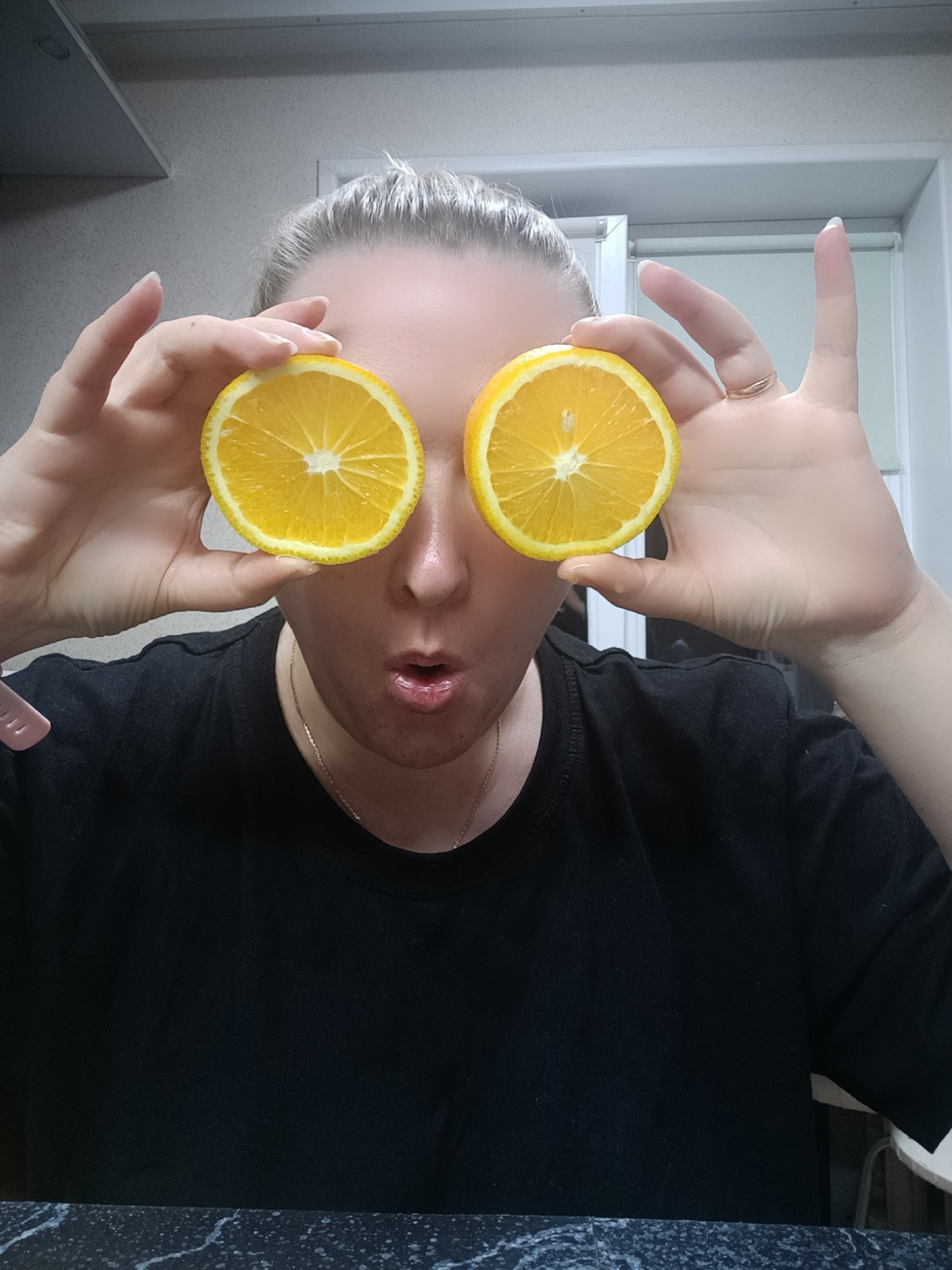Woman poses playfully with orange slices in Russian kitchen