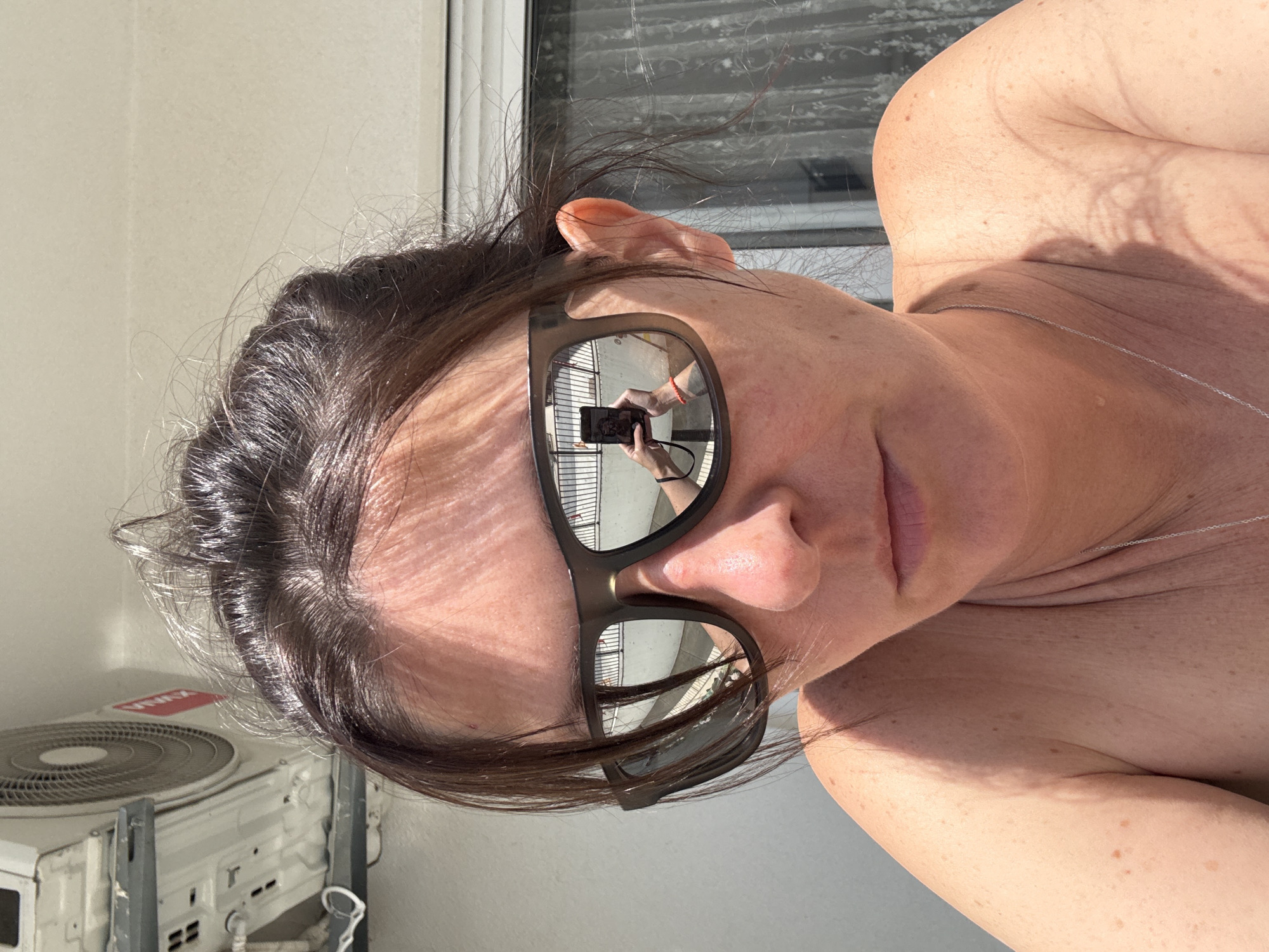 Tourist captures sunglasses selfies reflecting Bar cityscape
