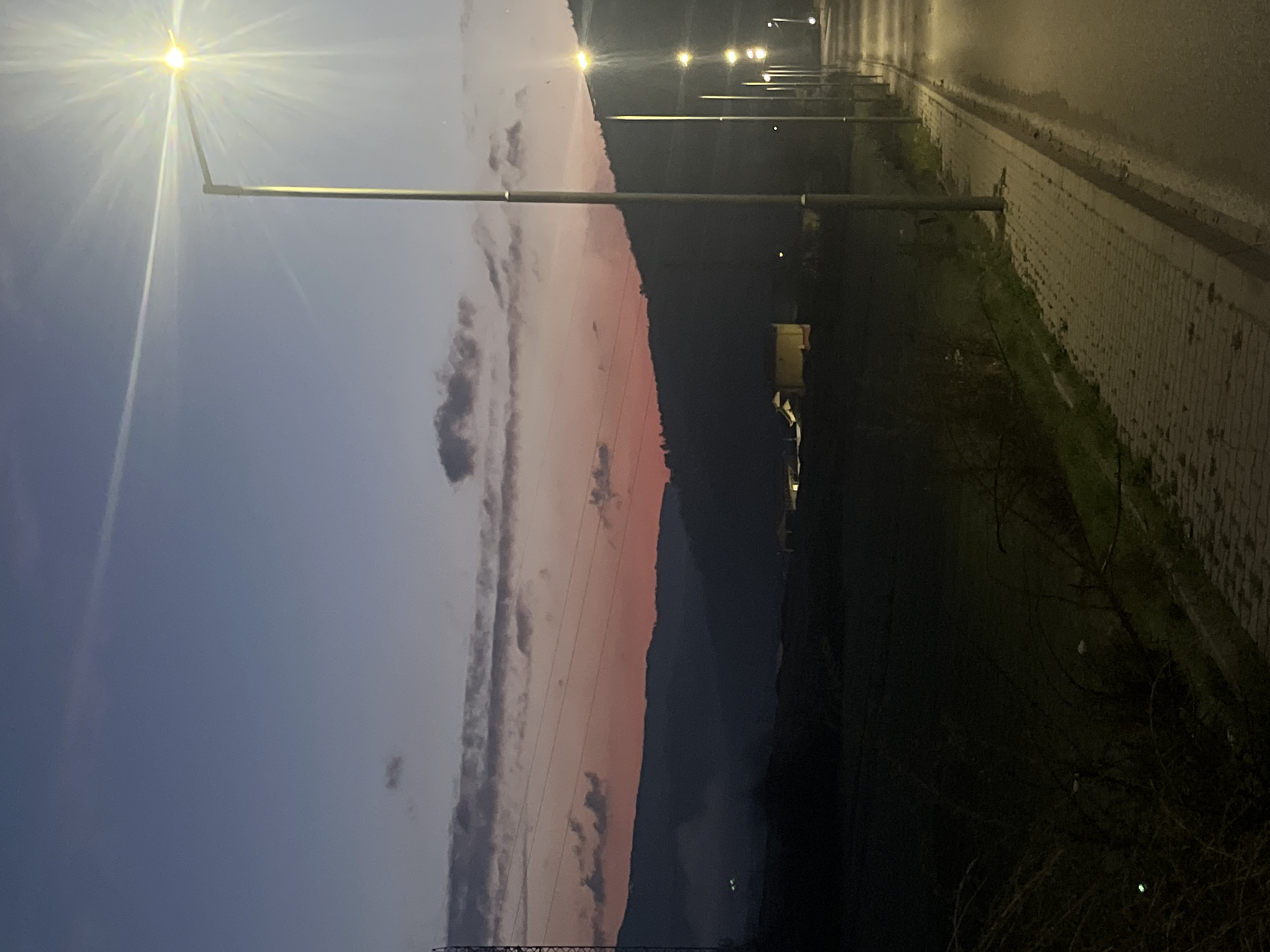 Nighttime streetlights illuminate roadside path in Velingrad, Bulgaria