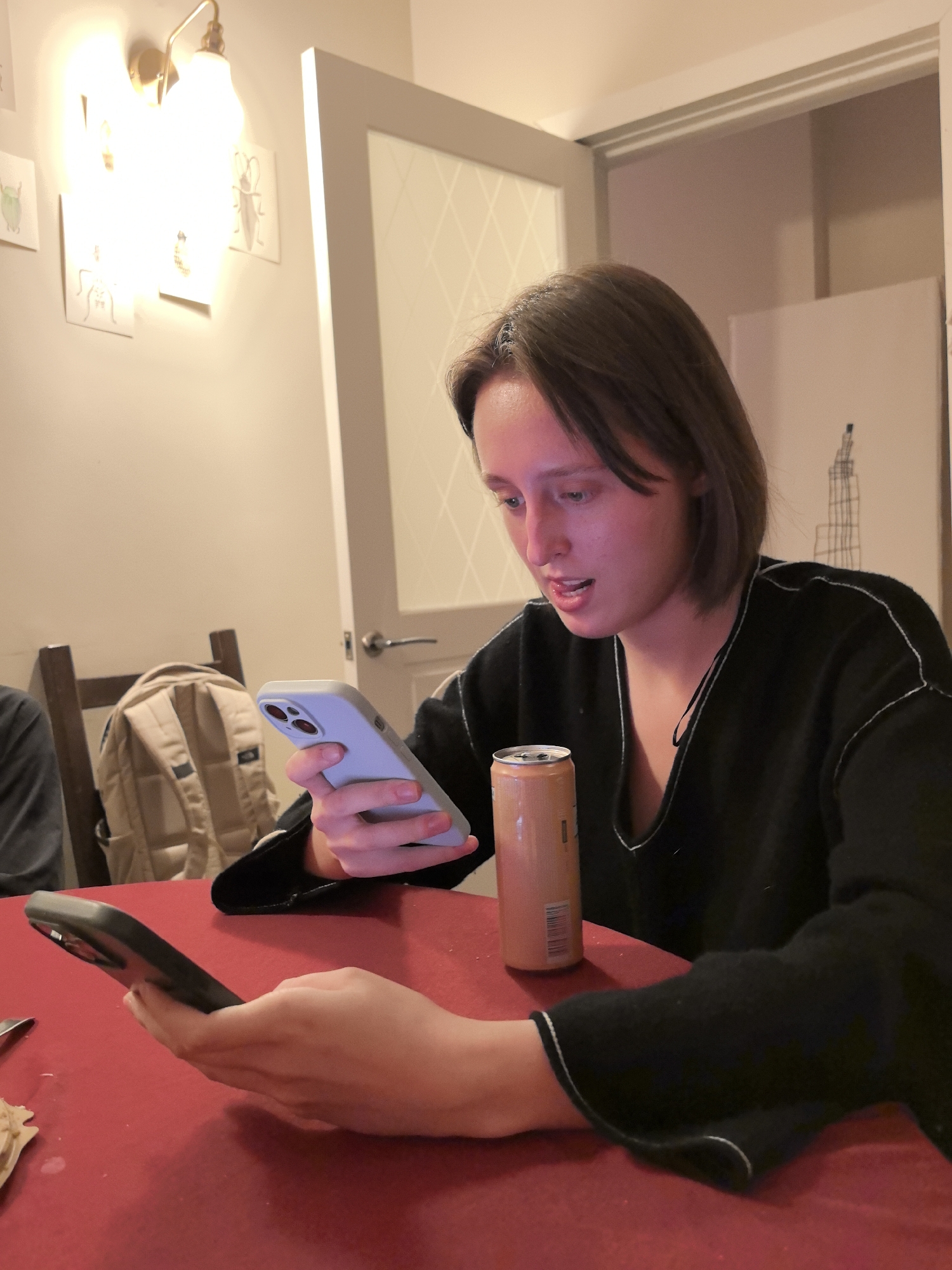 Person Uses Two Smartphones Simultaneously at Indoor Red Table