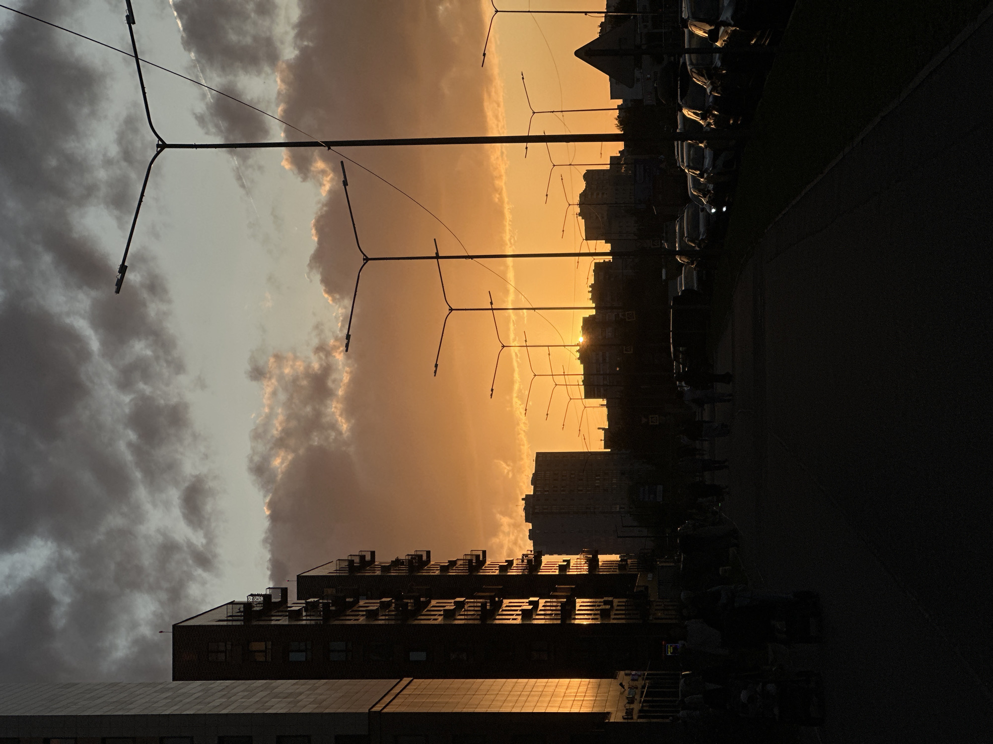 Warm orange sunset behind Kudrovo's skyline