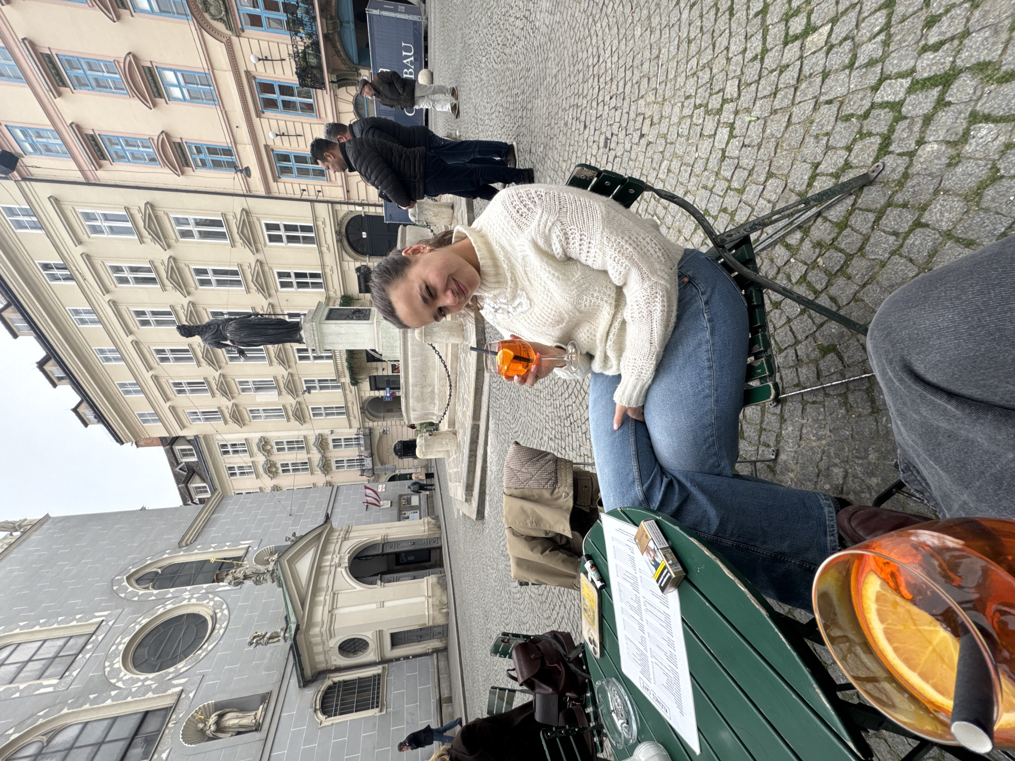 Woman enjoys orange drink at outdoor Vienna cafe