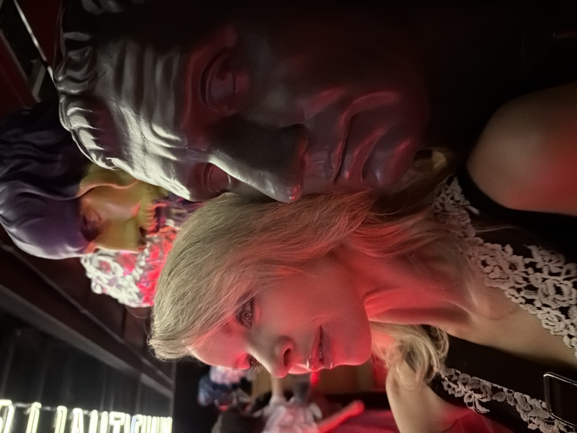 Woman leans against classical bust under red lighting in Moscow