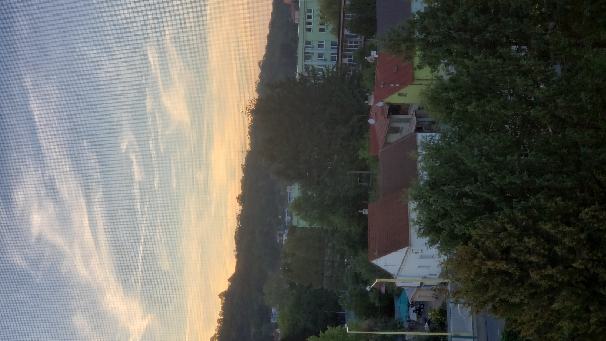Sunset over Prešov's wooded hills, watched through a window