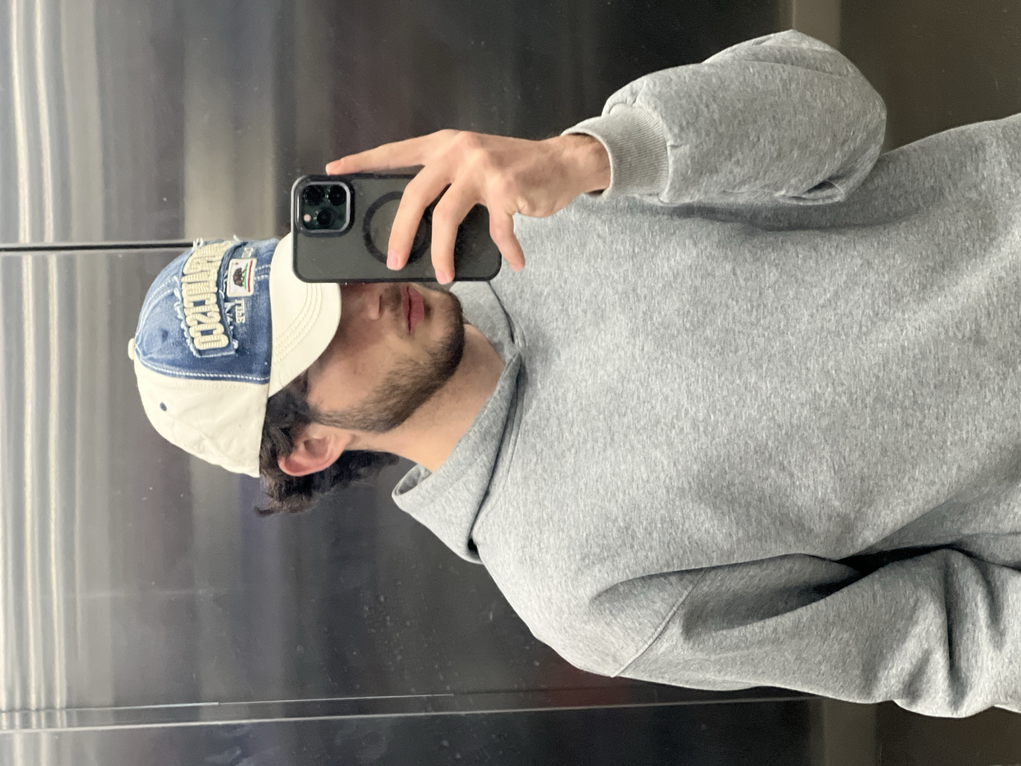Man takes selfie in Yerevan elevator wearing hoodie and cap