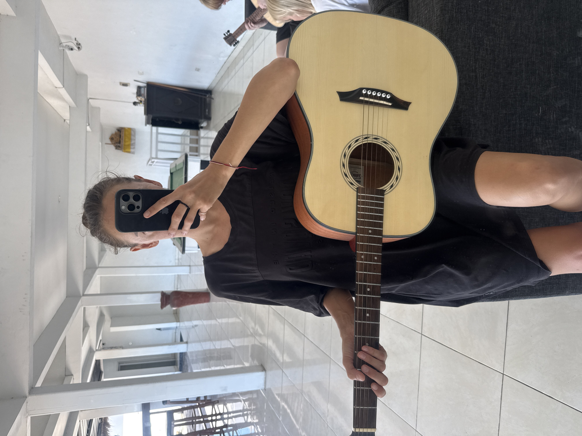 Person takes mirror selfie with acoustic guitar in Kuta