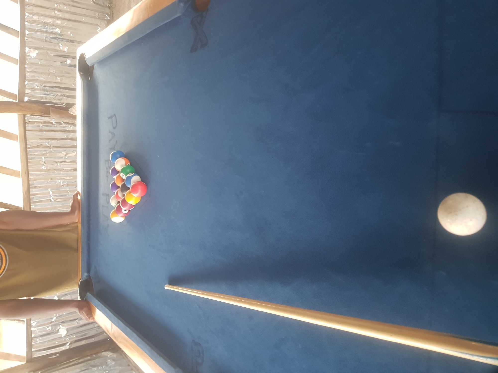 Pool game at a rustic open-air billiard table