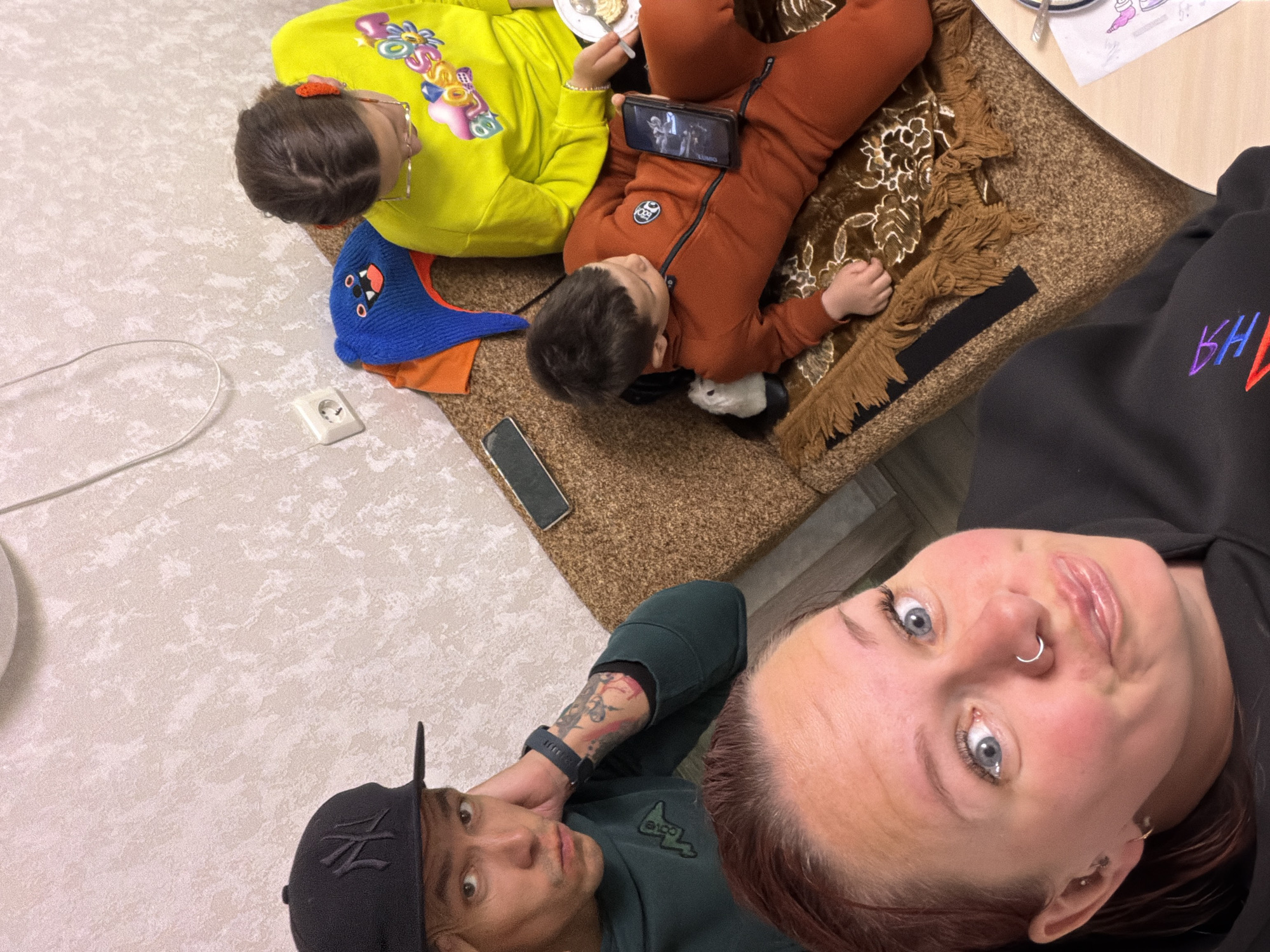 Four people gather indoors in Chaikovsky, children on rug