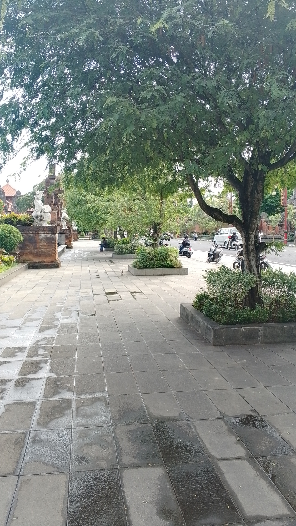 Balinese public park: warrior statues, fountains, and a sleeping dog