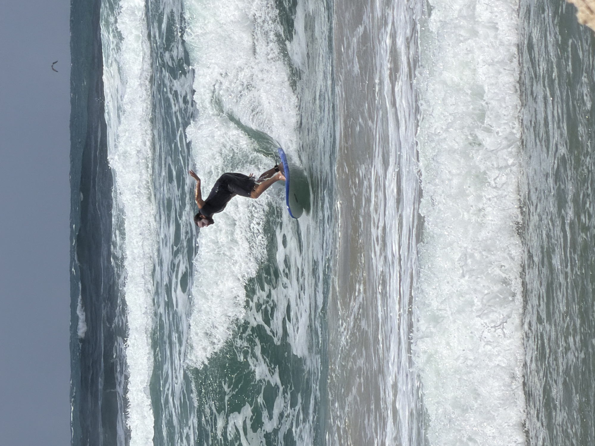 Man skimboards in choppy waters off Tel Aviv beach