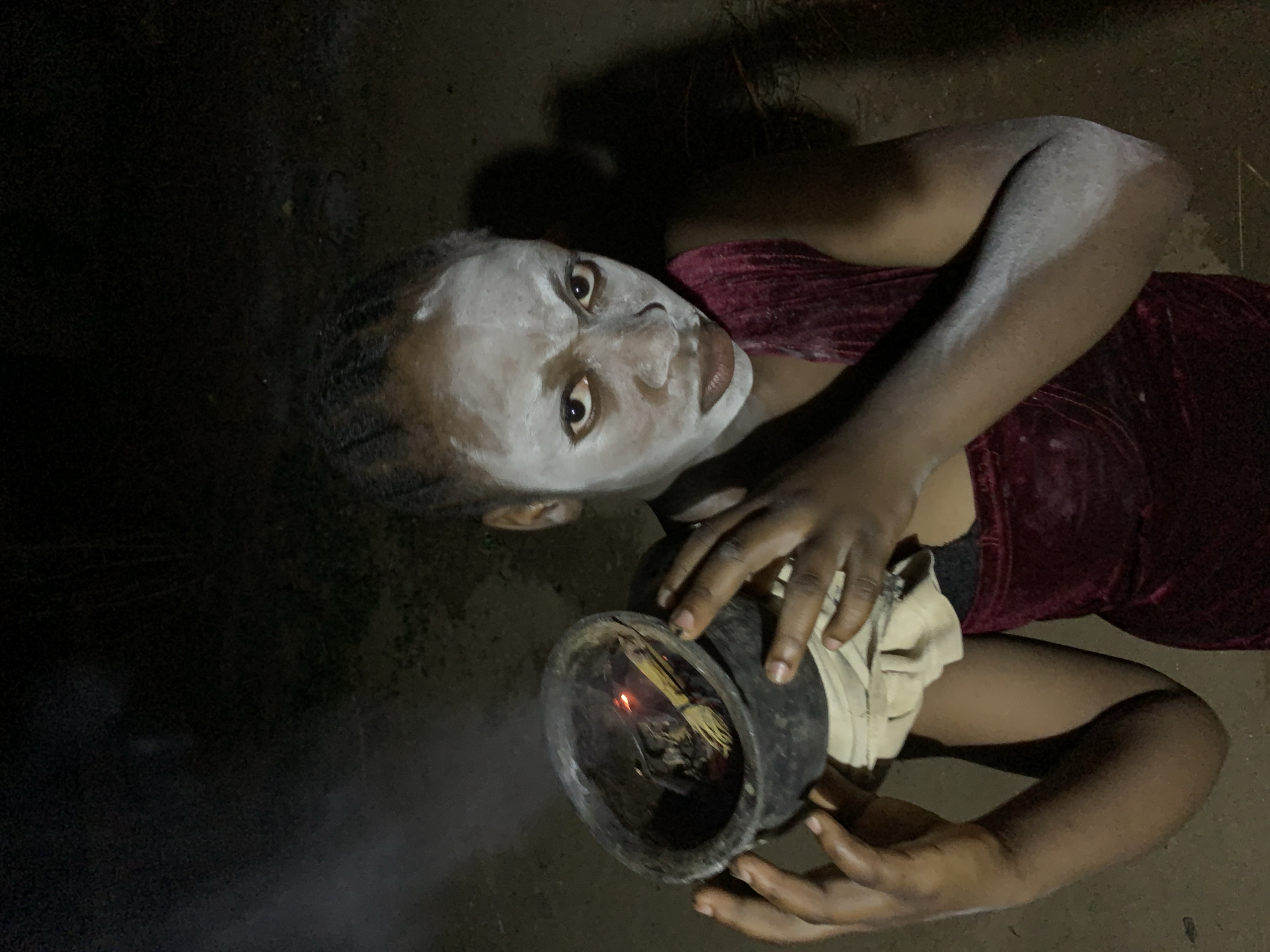 Woman holds smoking pot with white face paint in Nigeria