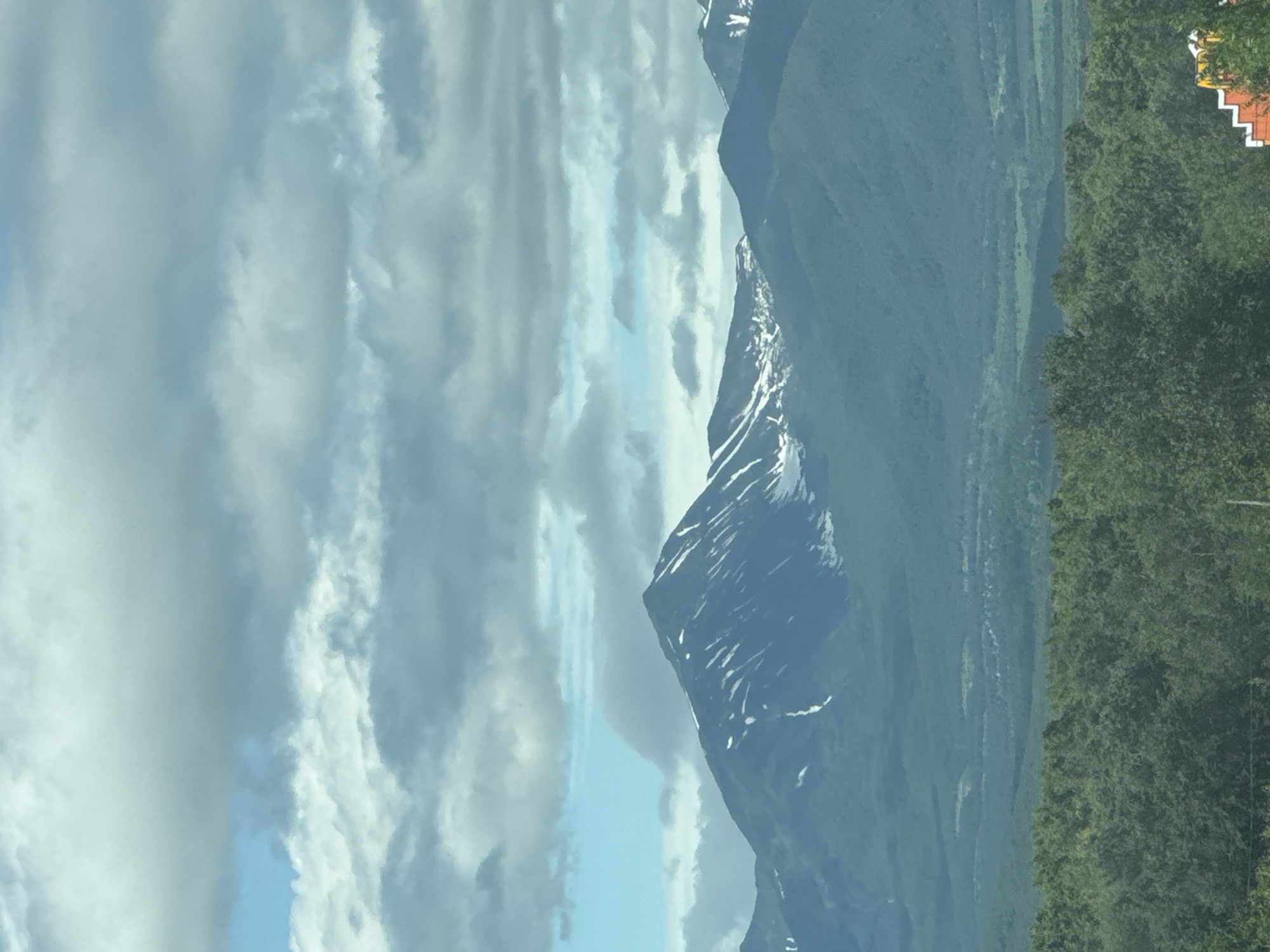 Snow-streaked volcanic peak towers over forested Nagornyi, Russia