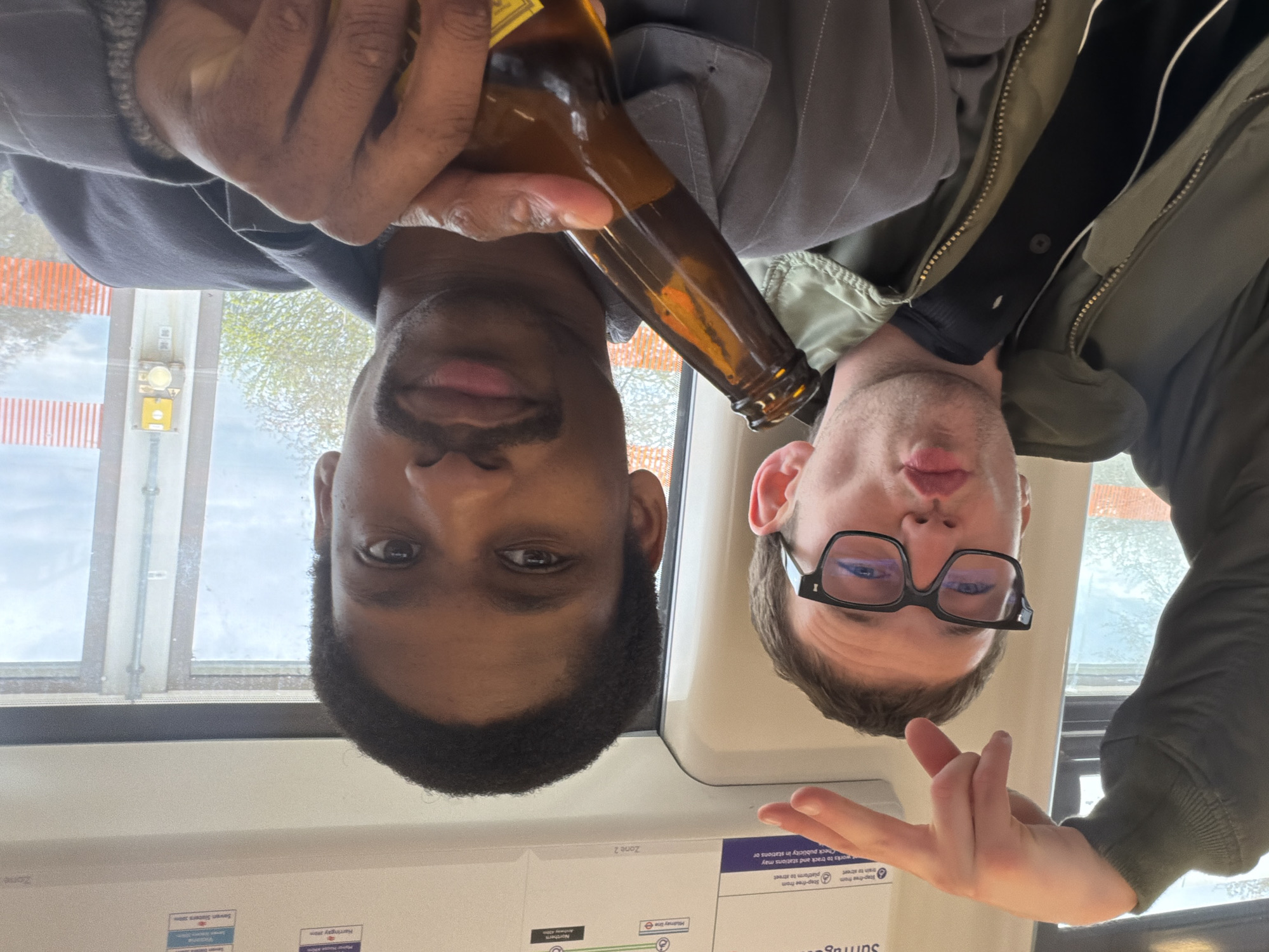 Two men share drinks on London Underground train