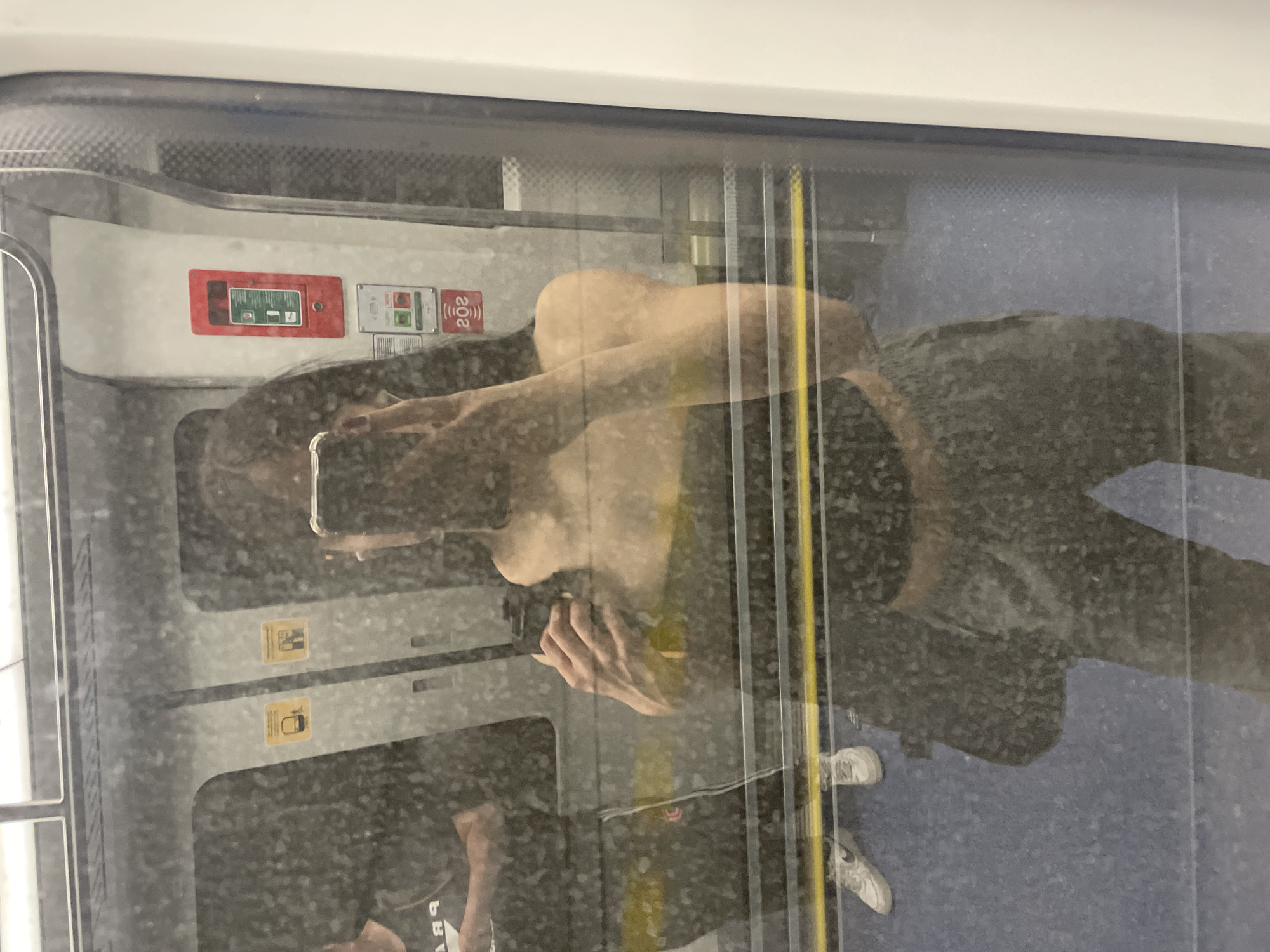 Train passenger reflection captured in Milan transit window