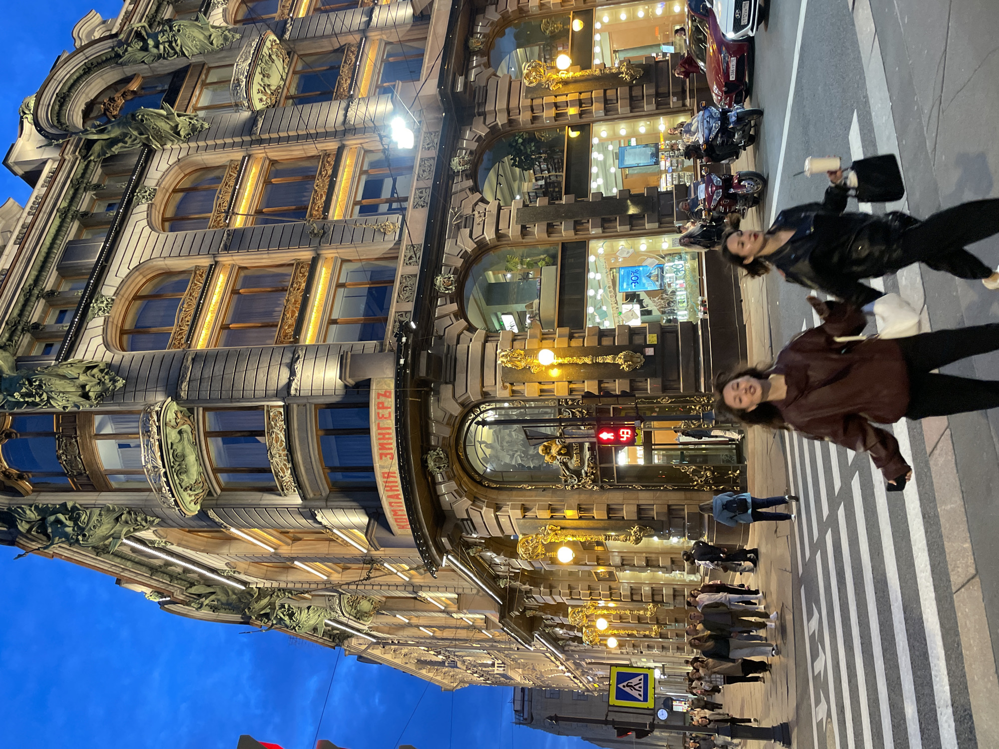 Evening street activity outside a lit ornate European building