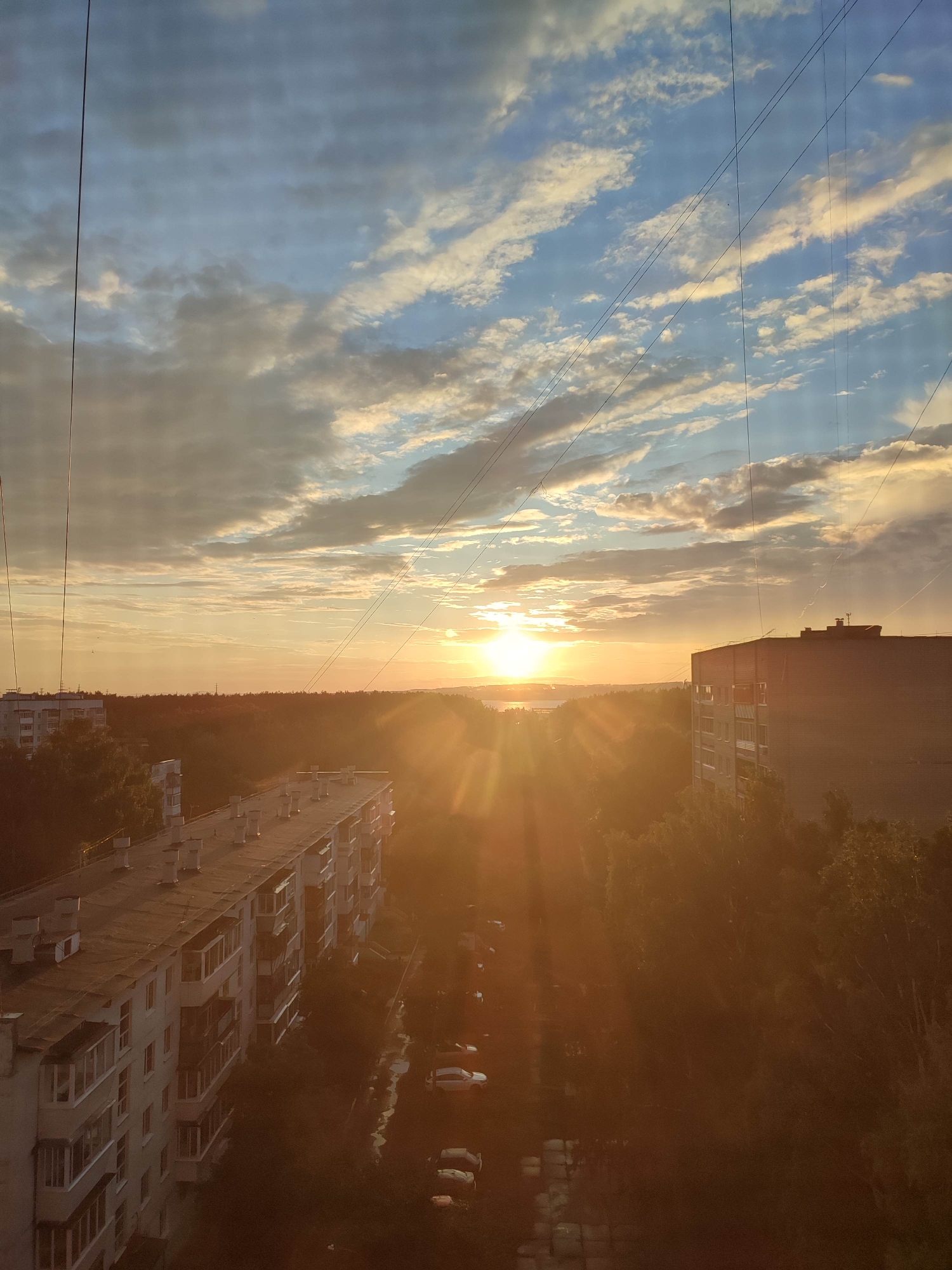 Sun observed over residential city skyline June 12