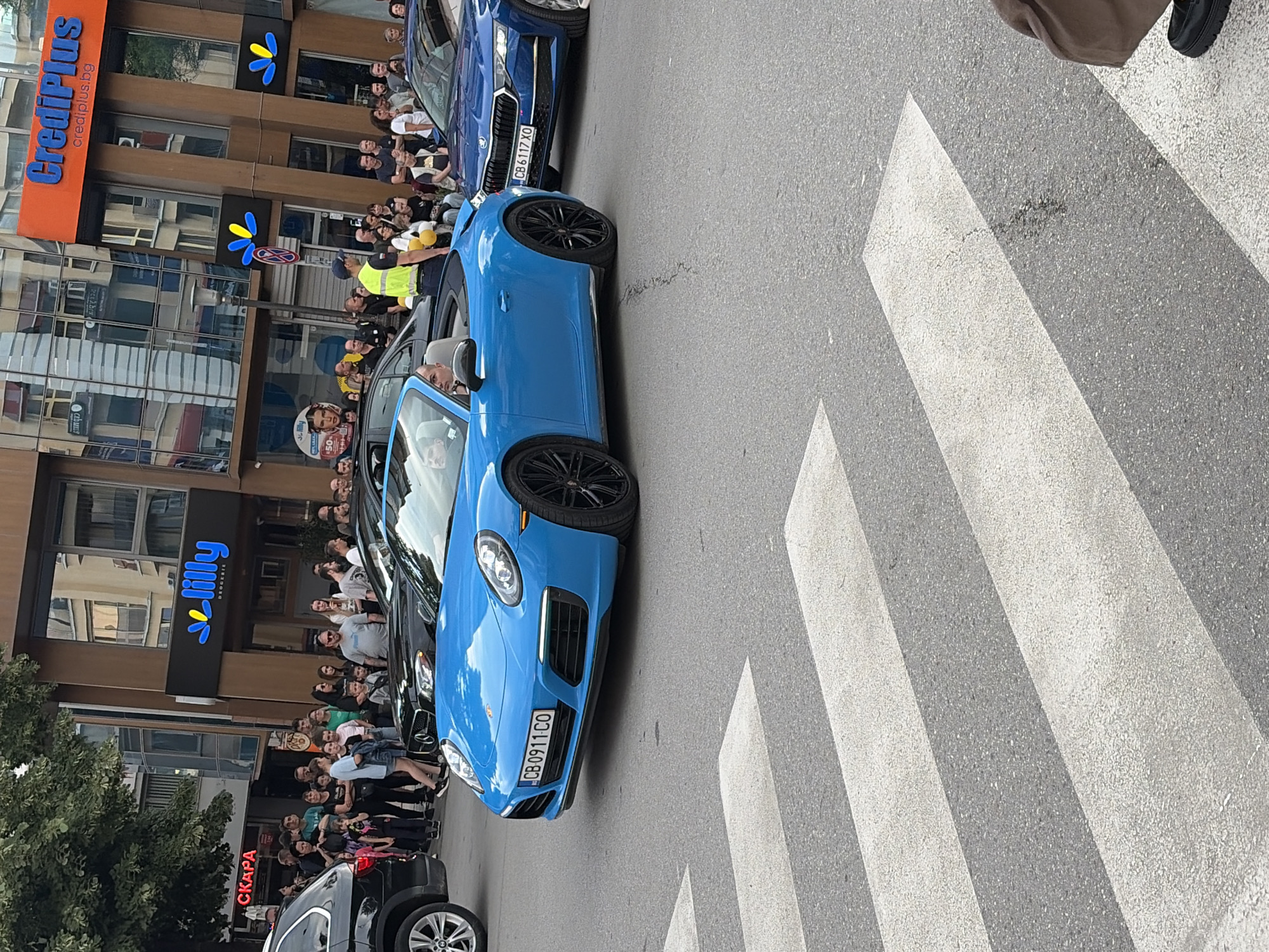 Luxury car parade with balloon-decorated motorcycles draws street crowds