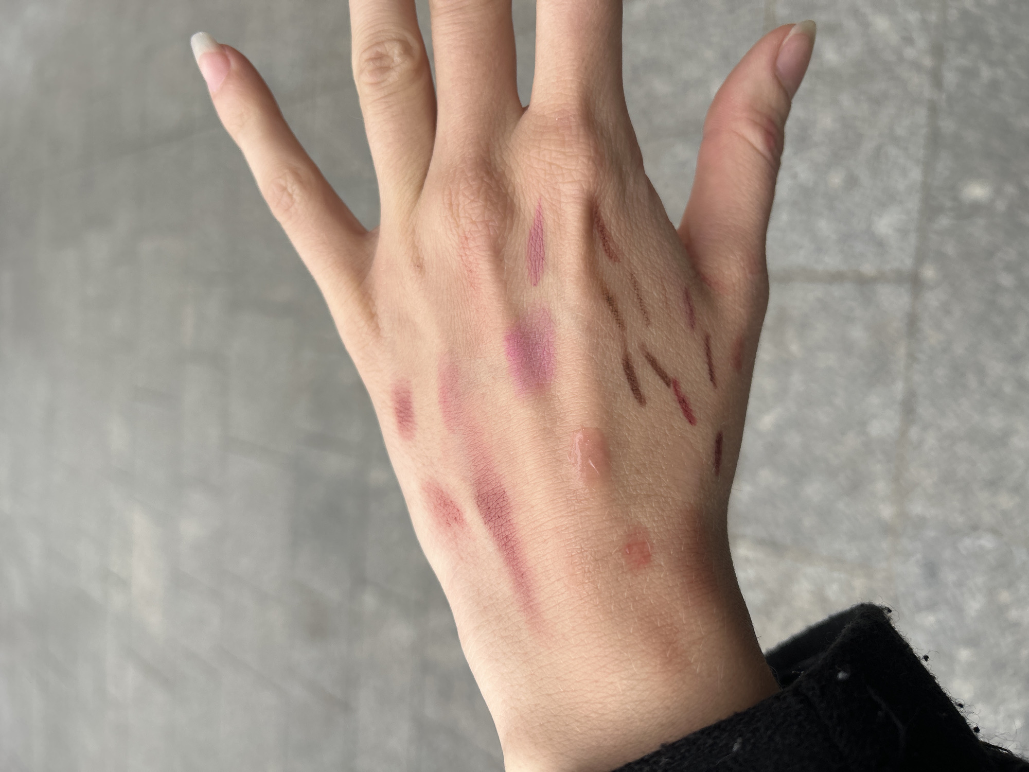 Person tests cosmetic swatches on hand in Paris