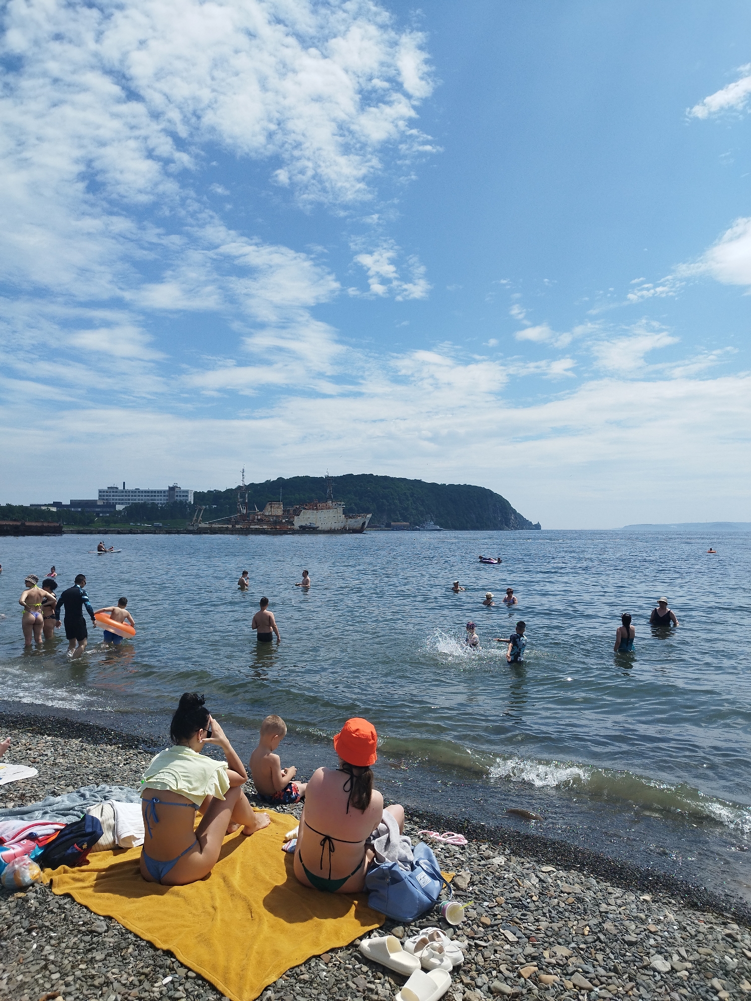 Summer day at a Vladivostok pebble beach, Golden Horn Bay backdrop.