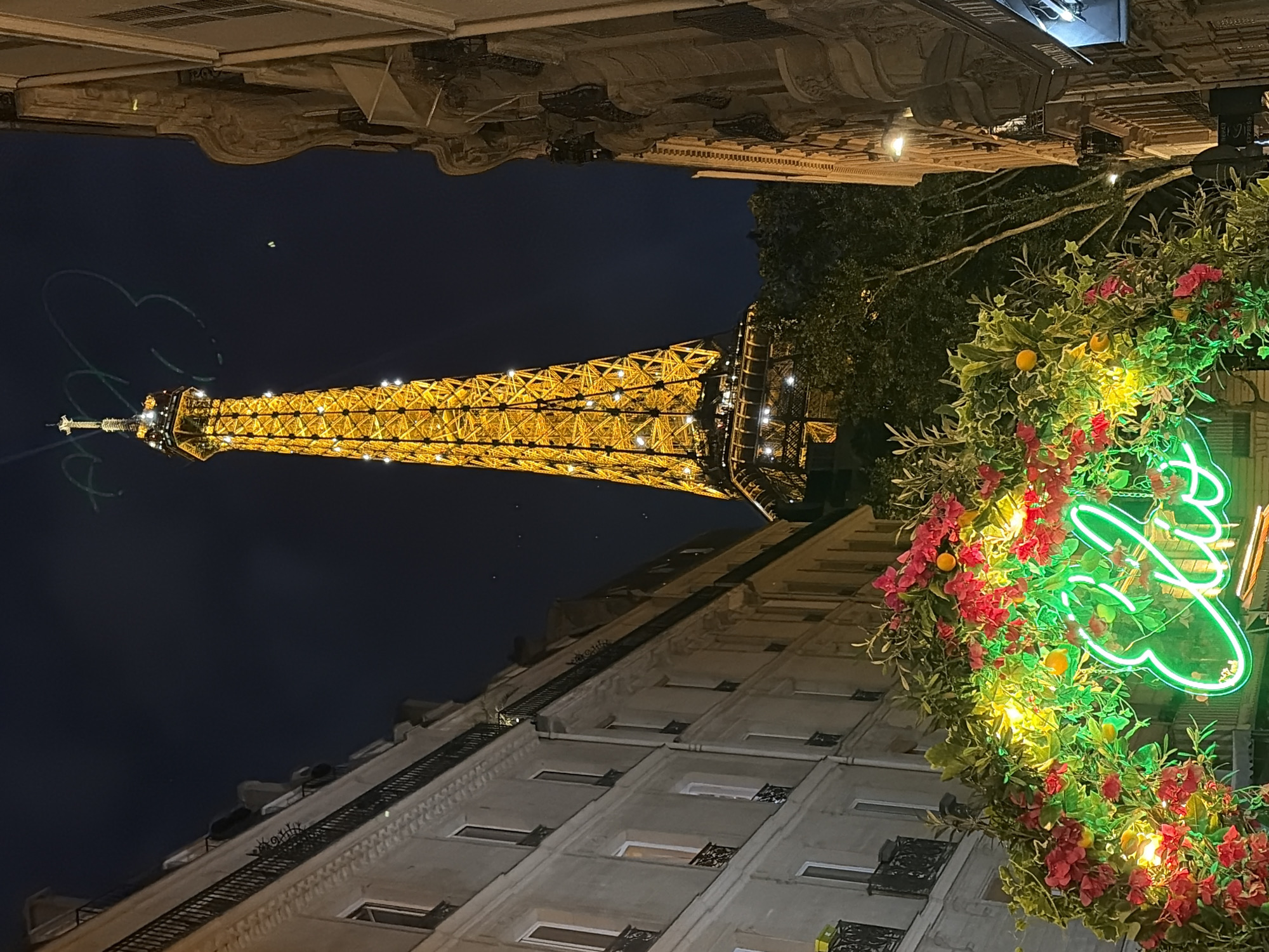 Eiffel Tower lit up at night, framed by a floral archway