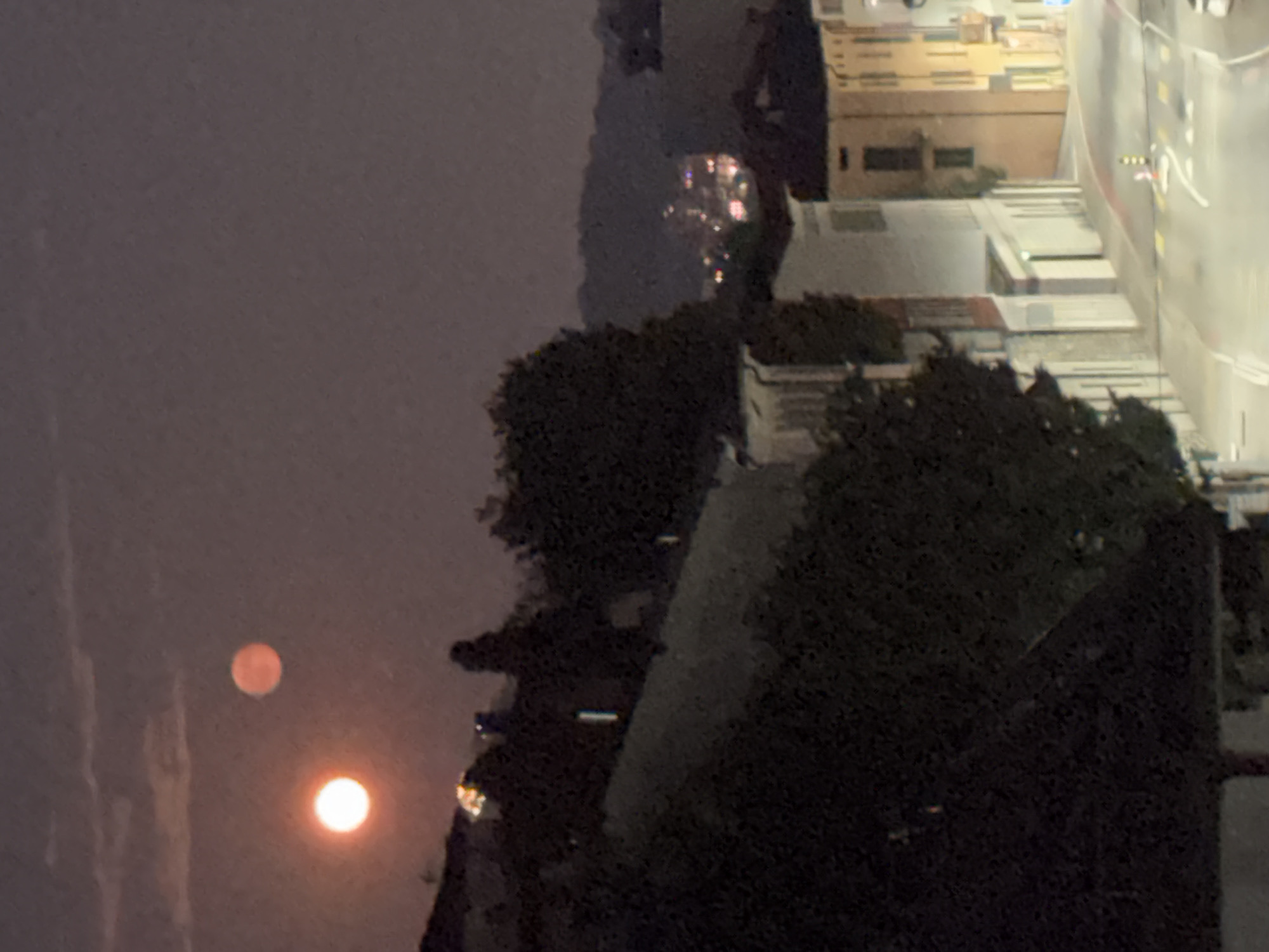 Orange full moon rises over a wet Balerna street at night