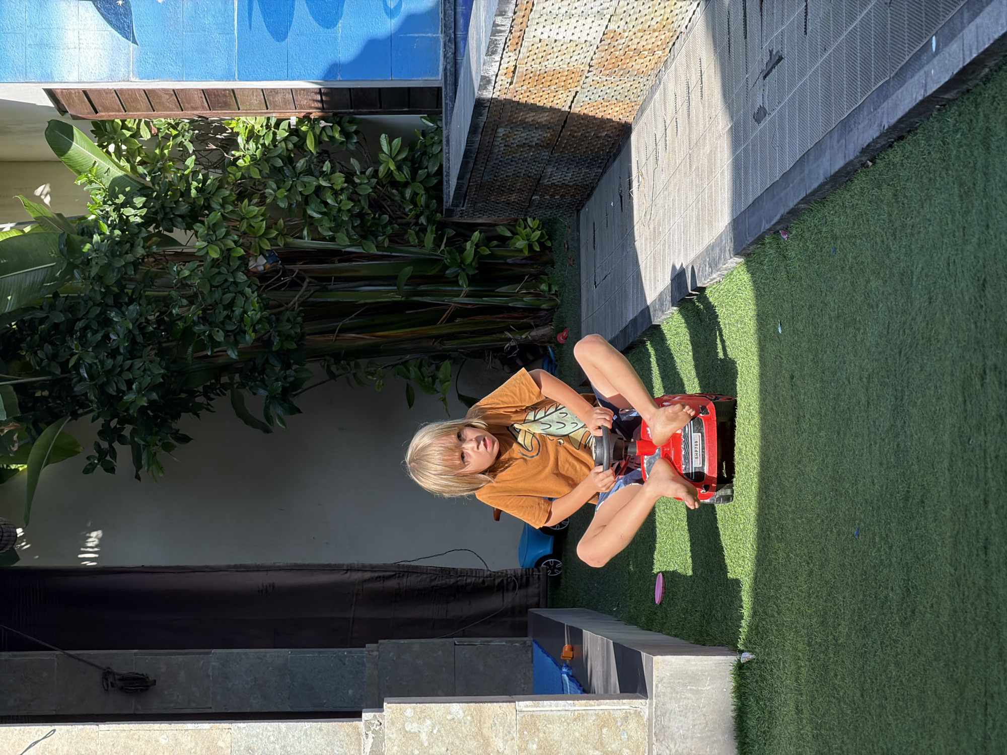 Children interact with gecko during pool playtime in Kuta