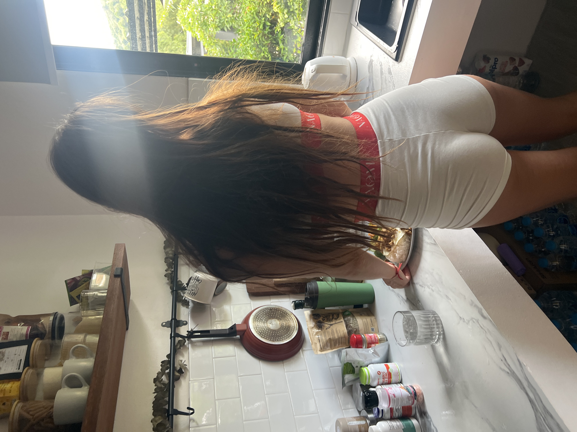 Woman multitasks cooking and laptop work in Thai home