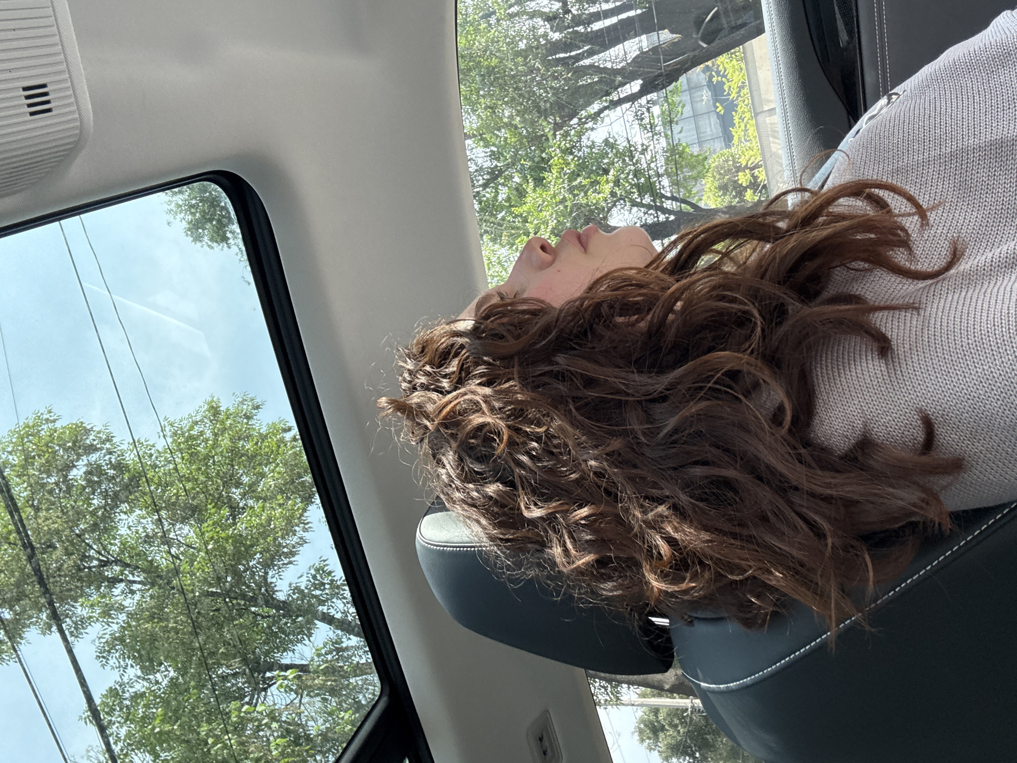 Woman rests in passenger seat during evening drive in Mexico City