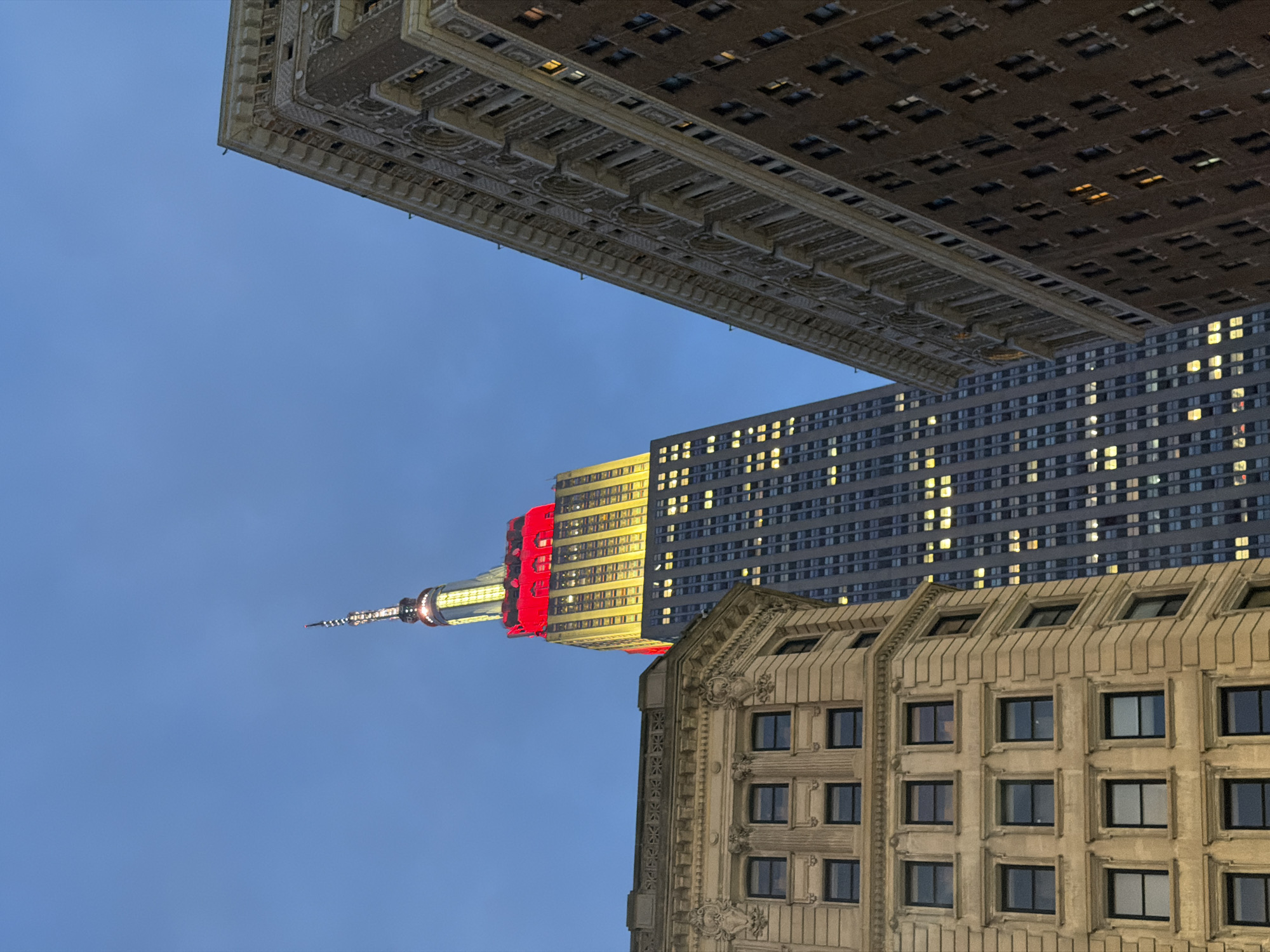 Empire State Building glowing red and yellow on a Midtown night