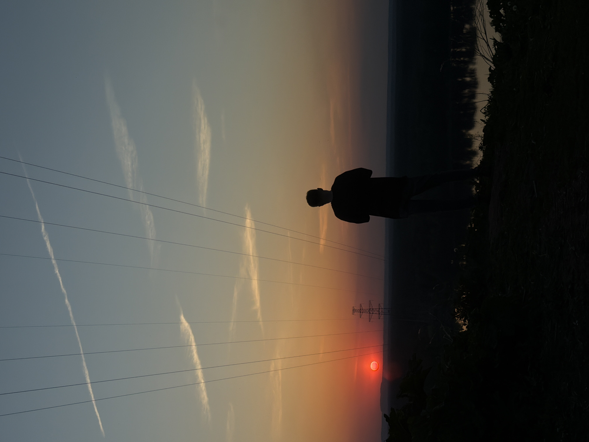 Couple photographs sunset near power lines in Noviy, Russia