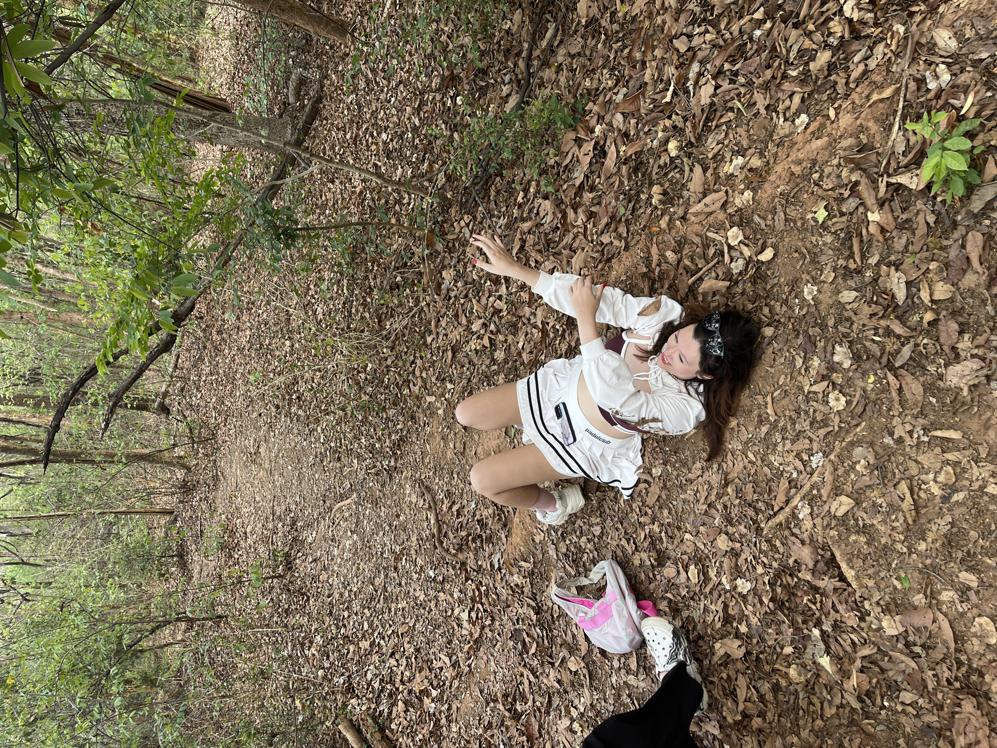 Woman in white lies on wooded path in Chiang Mai