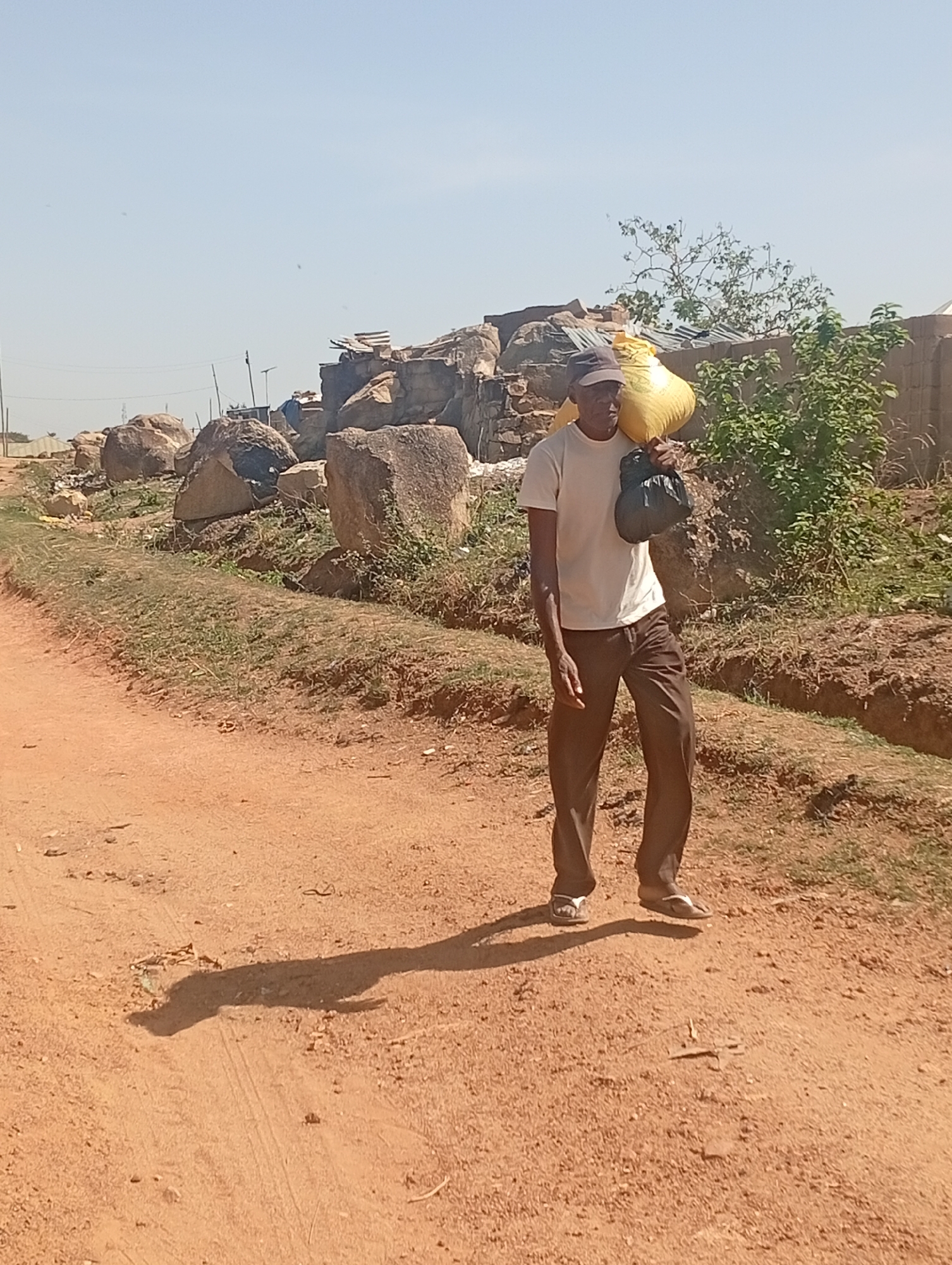 Man carries large sack while walking dirt road in Nigeria