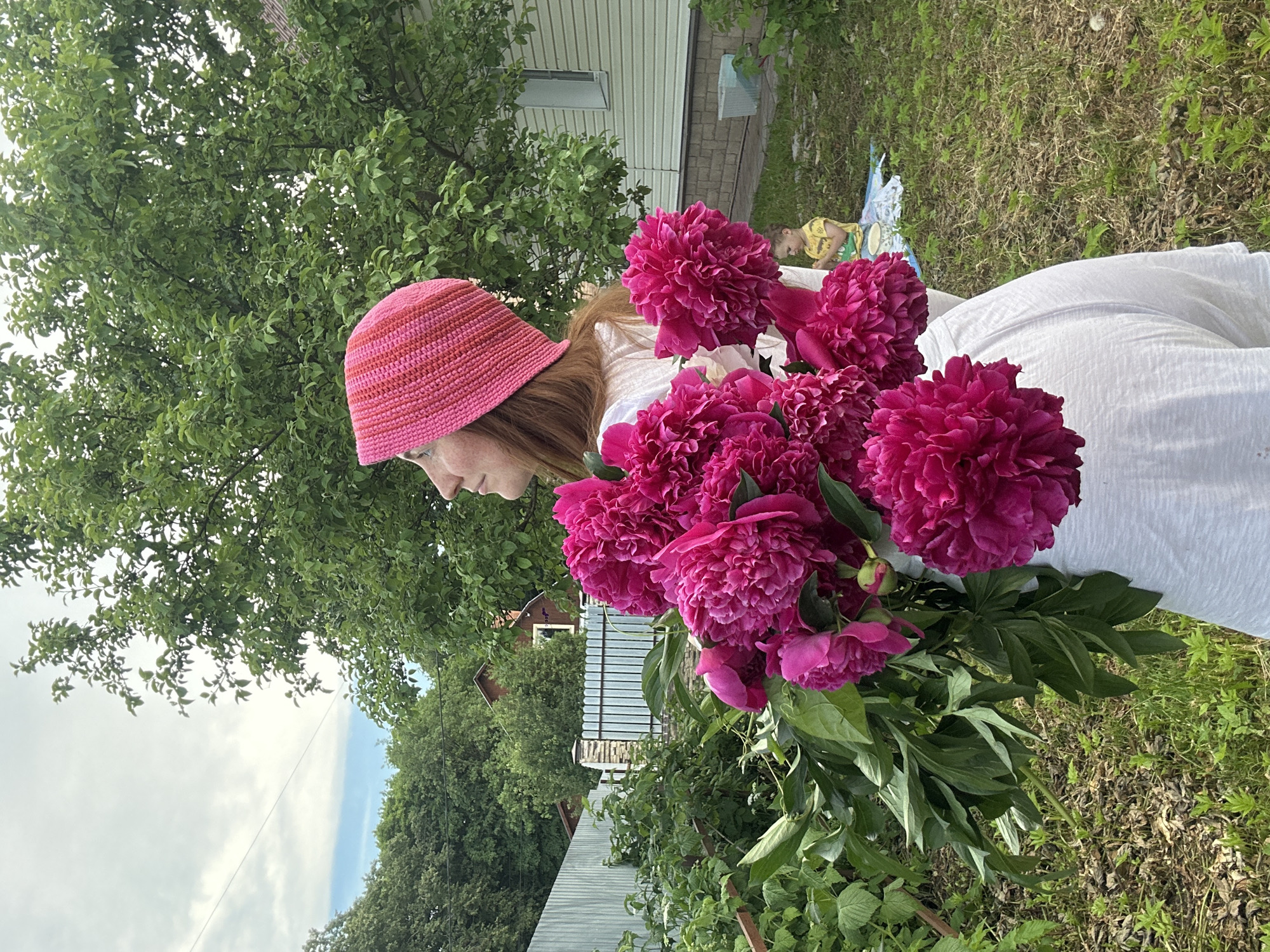 Woman poses with pink peonies in Nizhny Novgorod backyard photoshoot
