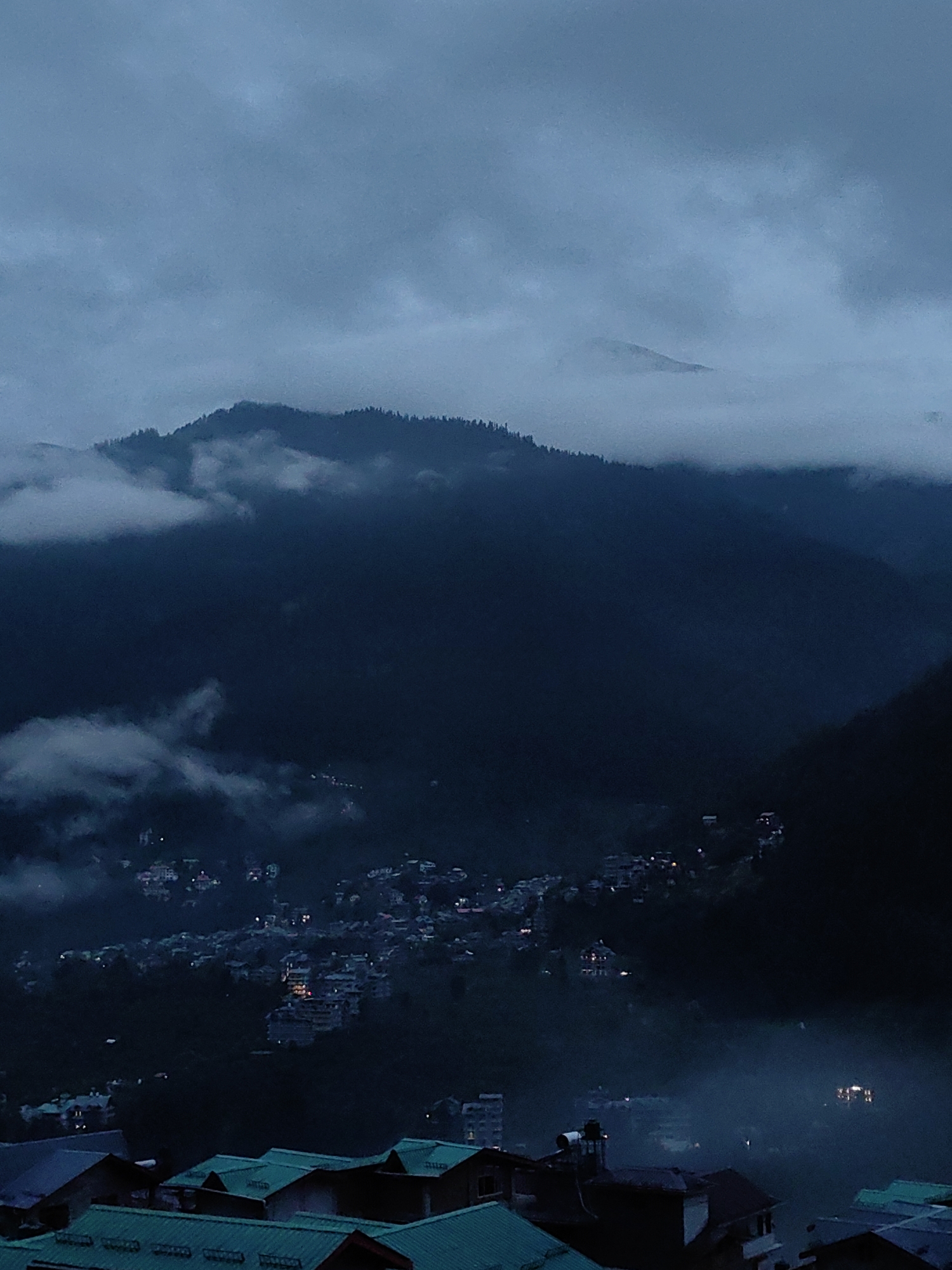 Fog and dusk settle over Vashisht's misty mountain valley